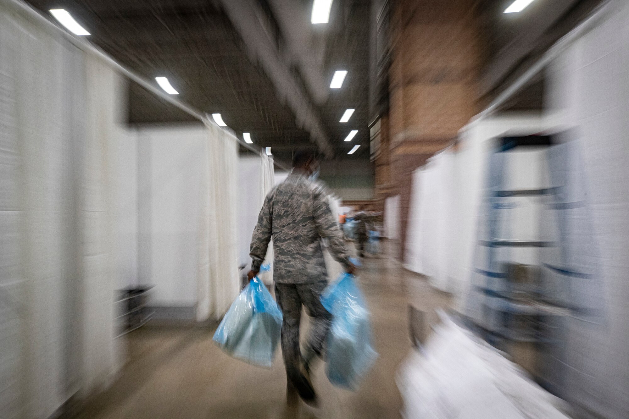 A New Jersey Air National Guard Airman carries supplies during the buildup of a Field Medical Station at the Atlantic City Convention Center in Atlantic City, N.J., April 9, 2020.  Atlantic City is one of three stations that will offer overflow from local hospitals focused on COVID-19 patients. (U.S. Air National Guard photo by Master Sgt. Matt Hecht)