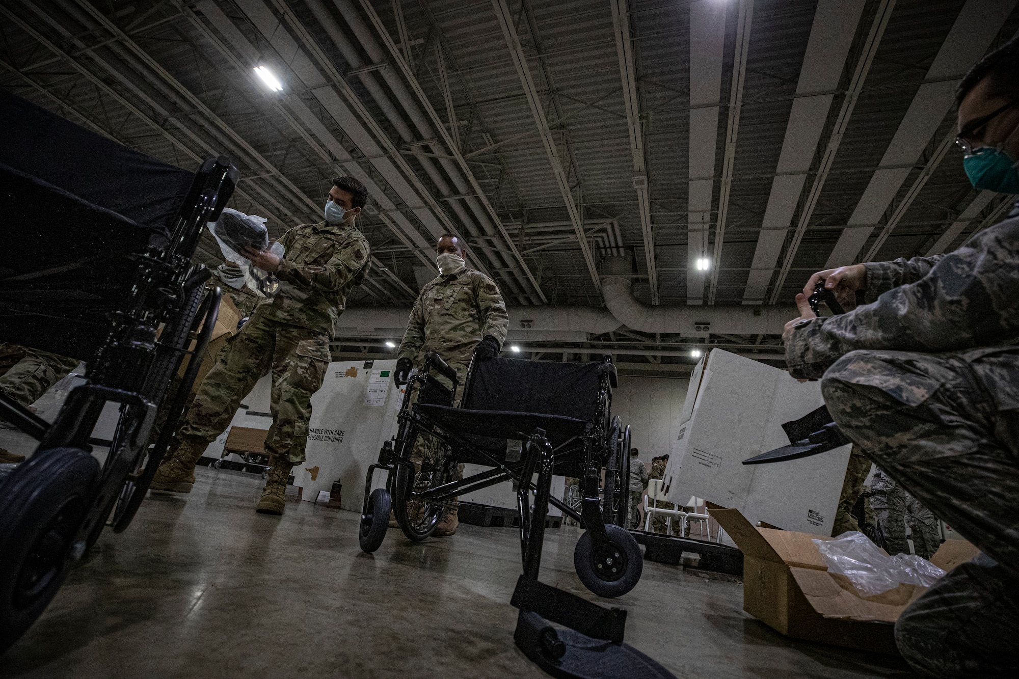 New Jersey Air National Guard Airmen put together wheelchairs during the buildup of a Field Medical Station at the Atlantic City Convention Center in Atlantic City, N.J., April 9, 2020.  Atlantic City is one of three stations that will offer overflow from local hospitals focused on COVID-19 patients. (U.S. Air National Guard photo by Master Sgt. Matt Hecht)