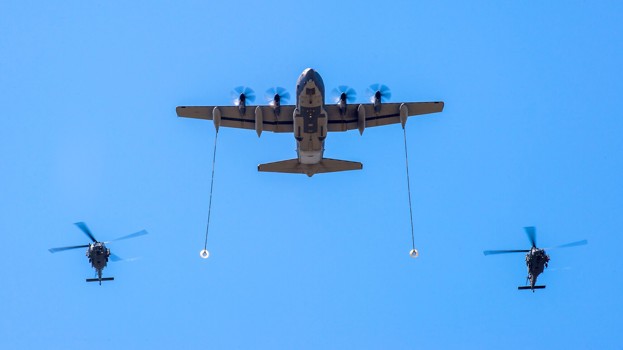 U.S. AIR FORCE ACADEMY, Colo. – Two HH-60 helicopters fly in formation with a C-130 showcasing a simulated air refueling operation on July 10, 2019 during a Combat Search and Rescue (CSAR) demonstration over the Terrazzo. The demonstration included a showcase of a variety of aircraft including four A-10s, two HH-60s, a C-130, a U-2 flyover. (U.S. Air Force photo/Trevor Cokley)