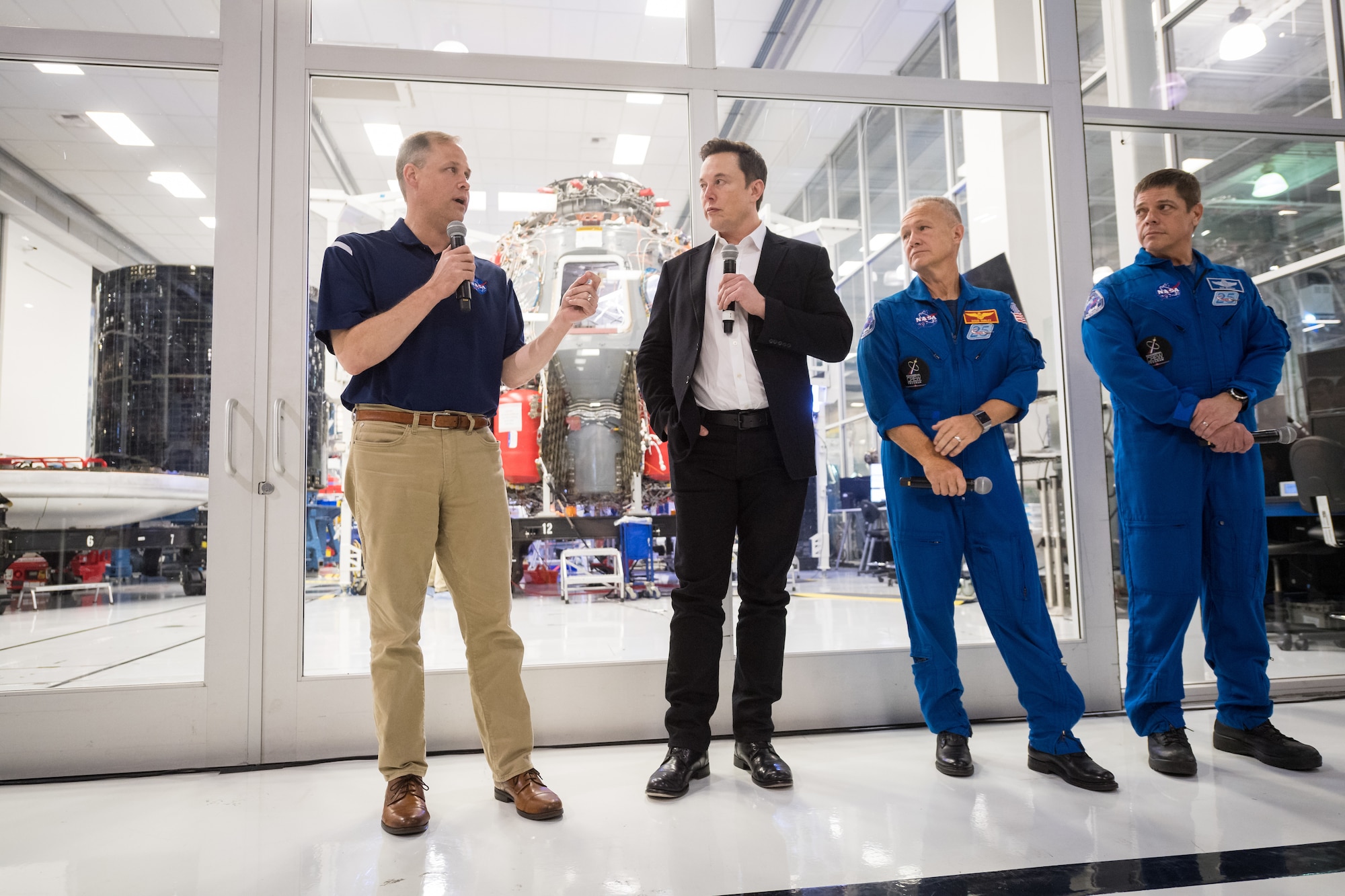 NASA Administrator Jim Bridenstine, left, speaks to press with SpaceX Chief Engineer Elon Musk, second from left, NASA astronaut Doug Hurley, second from right, and NASA astronaut Bob Behnken, in front of the Crew Dragon that is being prepared for the Demo-2 mission, at SpaceX Headquarters, Thursday, Oct. 10, 2019 in Hawthorne, CA. Photo credit: (NASA/Aubrey Gemignani)