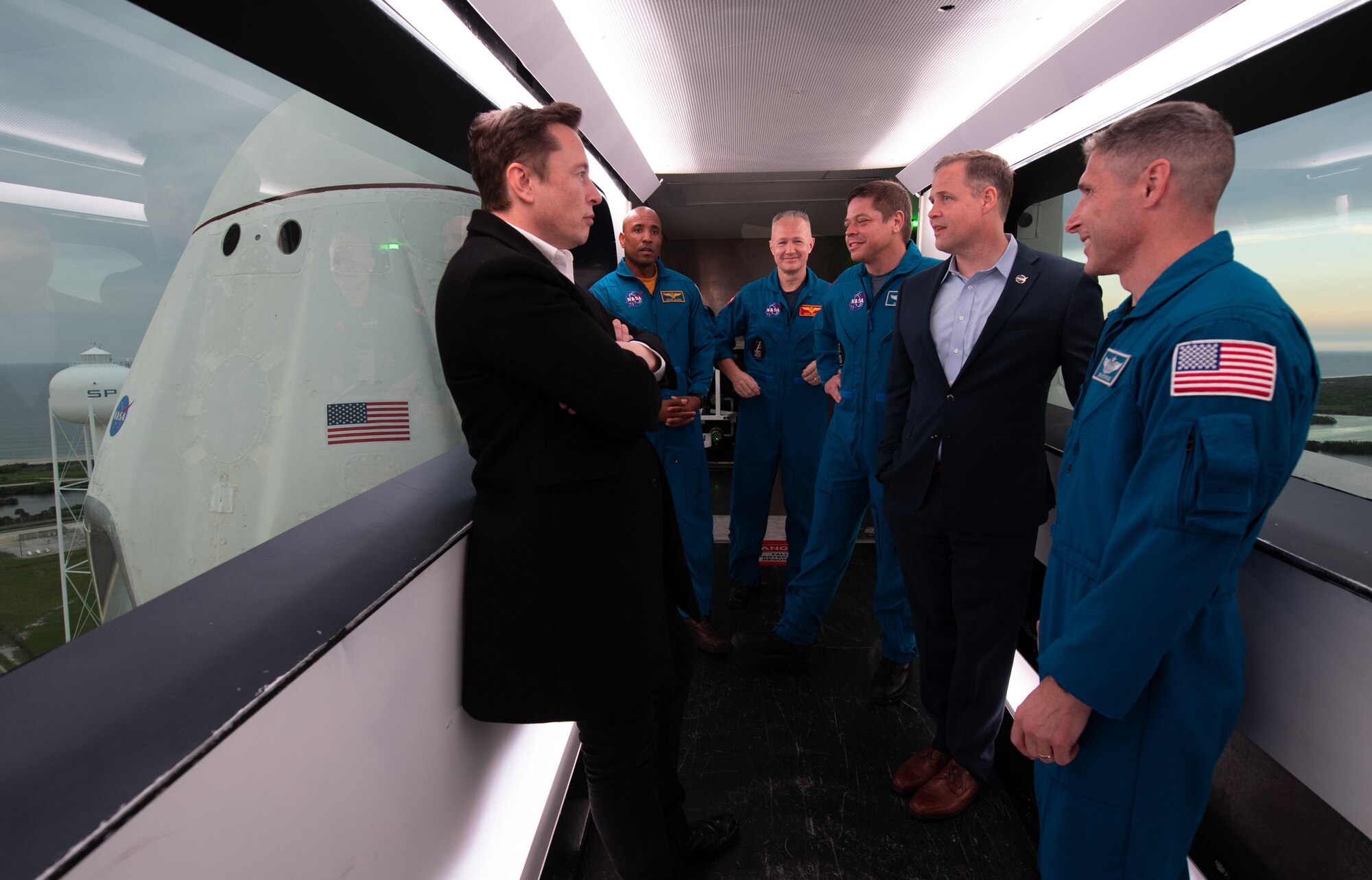 SpaceX CEO and Chief Designer Elon Musk, left, NASA astronauts Victor Glover, Doug Hurley, Bob Behnken, NASA Administrator Jim Bridenstine, and NASA astronaut Mike Hopkins are seen inside the crew access arm with the SpaceX Crew Dragon spacecraft visible behind them during a tour of Launch Complex 39A before the early Sunday morning launch of the Demo-1 mission, Friday, March 1, 2019 at the Kennedy Space Center in Florida. The Demo-1 mission launched at 2:49am ET on Saturday, March 2 and was the first launch of a commercially built and operated American spacecraft and space system designed for humans as part of NASA's Commercial Crew Program. The mission will serve as an end-to-end test of the system's capabilities. Hurley and Behnken are assigned to fly onboard Crew Dragon for the Demo-2 mission and Glover and Hopkins have been assigned to fly to the International Space Station on Crew Dragon's first operational mission. Photo Credit: (NASA/Joel Kowsky)