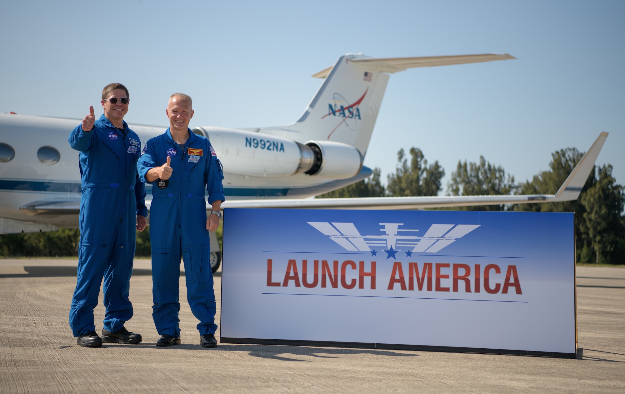NASA astronauts Robert Behnken, left, and Douglas Hurley gives a thumbs up after arriving at the Launch and Landing Facility at NASA’s Kennedy Space Center ahead of SpaceX’s Demo-2 mission, Wednesday, May 20, 2020, in Florida. NASA’s SpaceX Demo-2 mission is the first launch with astronauts of the SpaceX Crew Dragon spacecraft and Falcon 9 rocket to the International Space Station as part of the agency’s Commercial Crew Program. The flight test will serve as an end-to-end demonstration of SpaceX’s crew transportation system. Behnken and Hurley are scheduled to launch at 4:33 p.m. EDT on Wednesday, May 27, from Launch Complex 39A at the Kennedy Space Center. A new era of human spaceflight is set to begin as American astronauts once again launch on an American rocket from American soil to low-Earth orbit for the first time since the conclusion of the Space Shuttle Program in 2011.  Photo Credit: (NASA/Bill Ingalls)