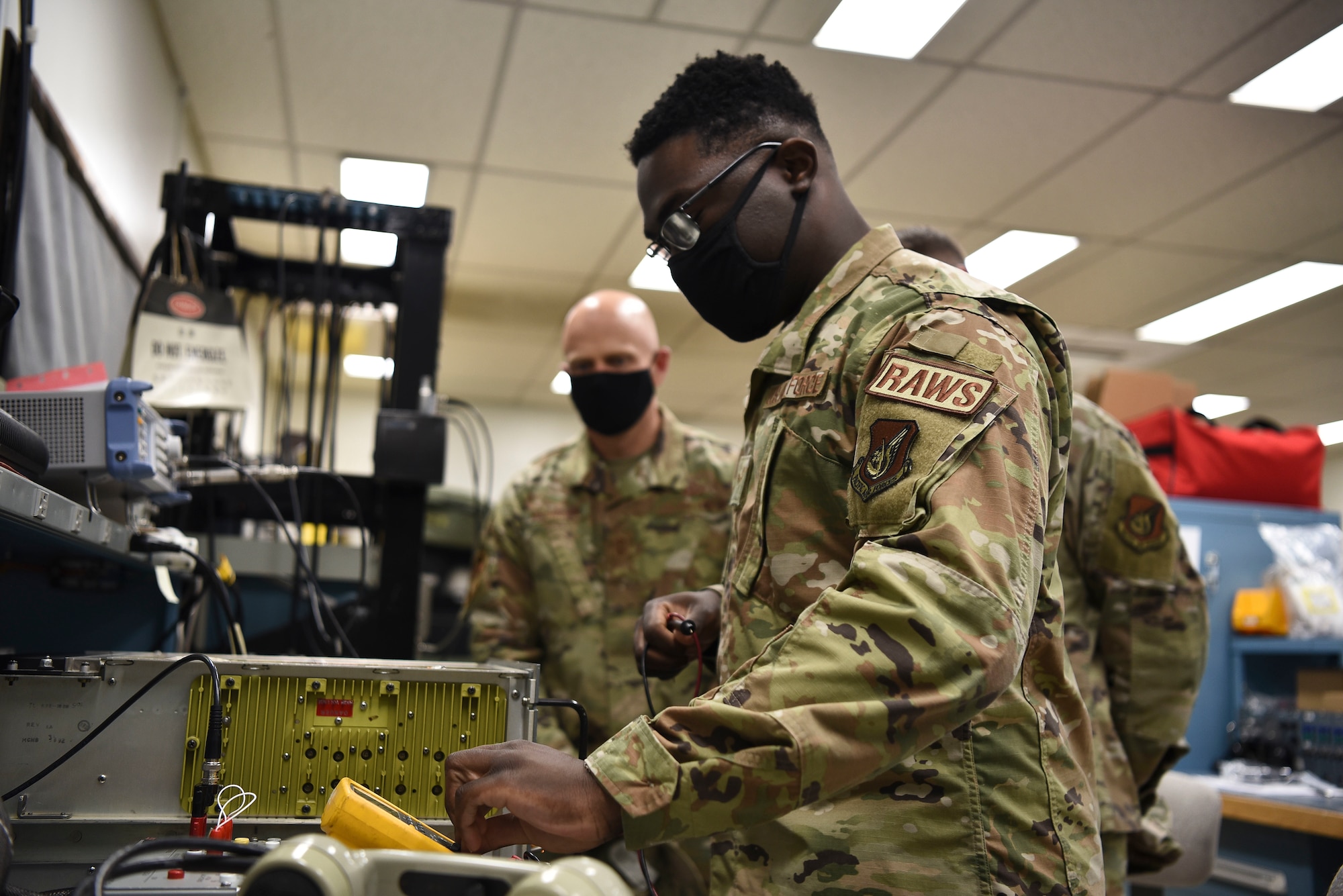 U.S. Air Force Airman 1st Class Simisola Mark, 35th Operations Support Squadron radar airfield weather system technician, uses a multimeter to test the voltage on an AN/GRC-171 transceiver for Col. Timothy Murphy, 35th Fighter Wing vice commander, and Chief Master Sgt. Joey Meininger, 35th Fighter Wing command chief, during a Wild Weasel Walk-Through at Misawa Air Base, Japan, May 24, 2021.