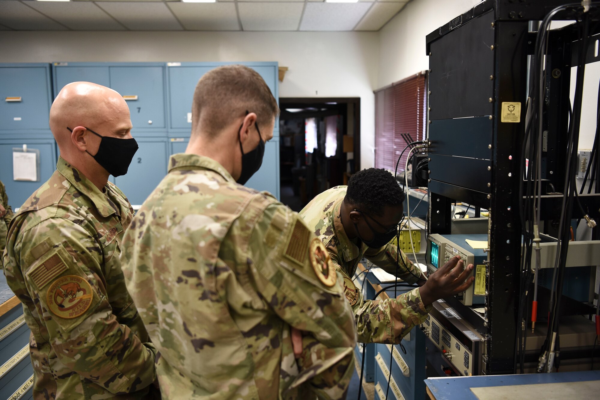 U.S. Air Force Airman 1st Class Simisola Mark, 35th Operations Support Squadron radar airfield weather system technician, adjusts an oscilloscope for Col. Timothy Murphy, 35th Fighter Wing vice commander, and Chief Master Sgt. Joey Meininger, 35th Fighter Wing command chief, in a Wild Weasel Walk-Through at Misawa Air Base, Japan, May 24, 2021.
