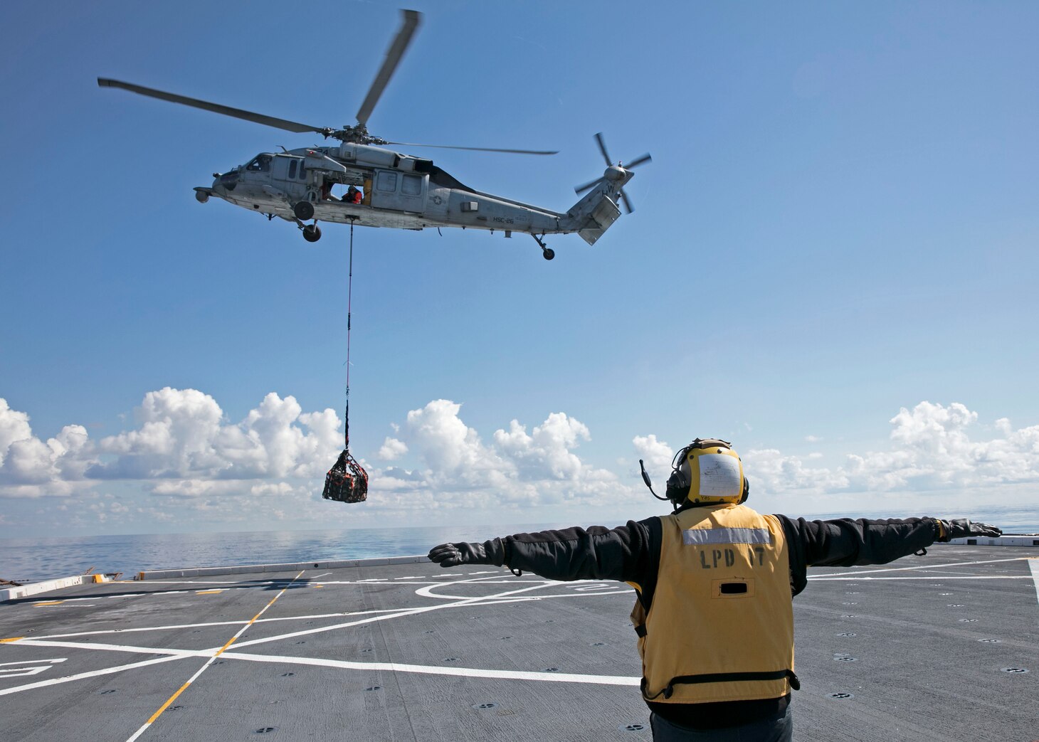 Aviation Boatswain's Mate (Handling) Airman Javier Carpio, assigned to the amphibious transport dock ship USS San Antonio (LPD 17), signals an MH-60S Sea Hawk helicopter from the "Chargers" of Helicopter Sea Combat Squadron (HSC) 26, during a vertical replenishment, May 1, 2021. San Antonio is operating in the Atlantic Ocean with Amphibious Squadron 4 and the 24th Marine Expeditionary Unit (24th MEU) as part of the Iwo Jima Amphibious Ready Group.