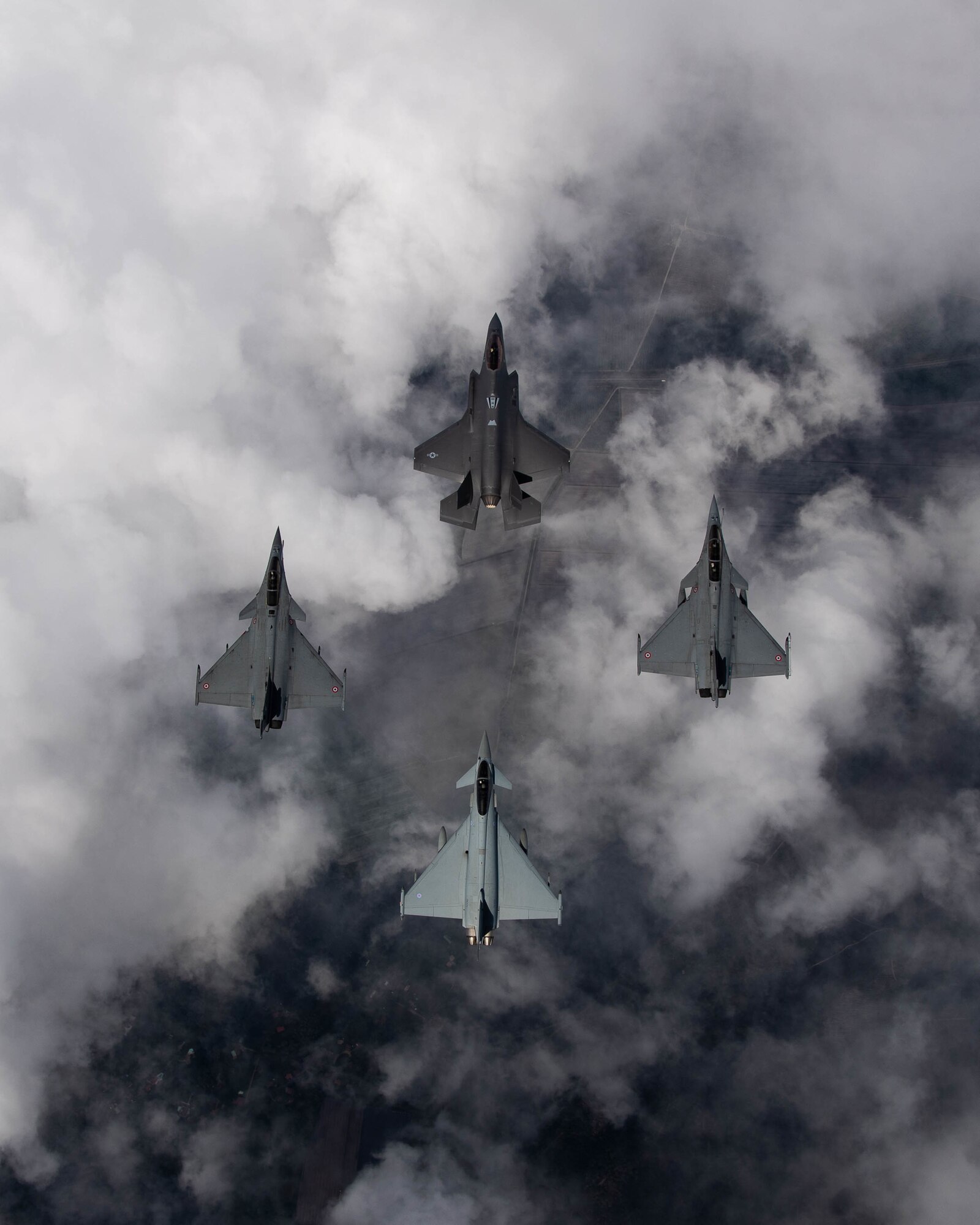 Four fighter aircraft flying in a diamond formation, looking at them from above