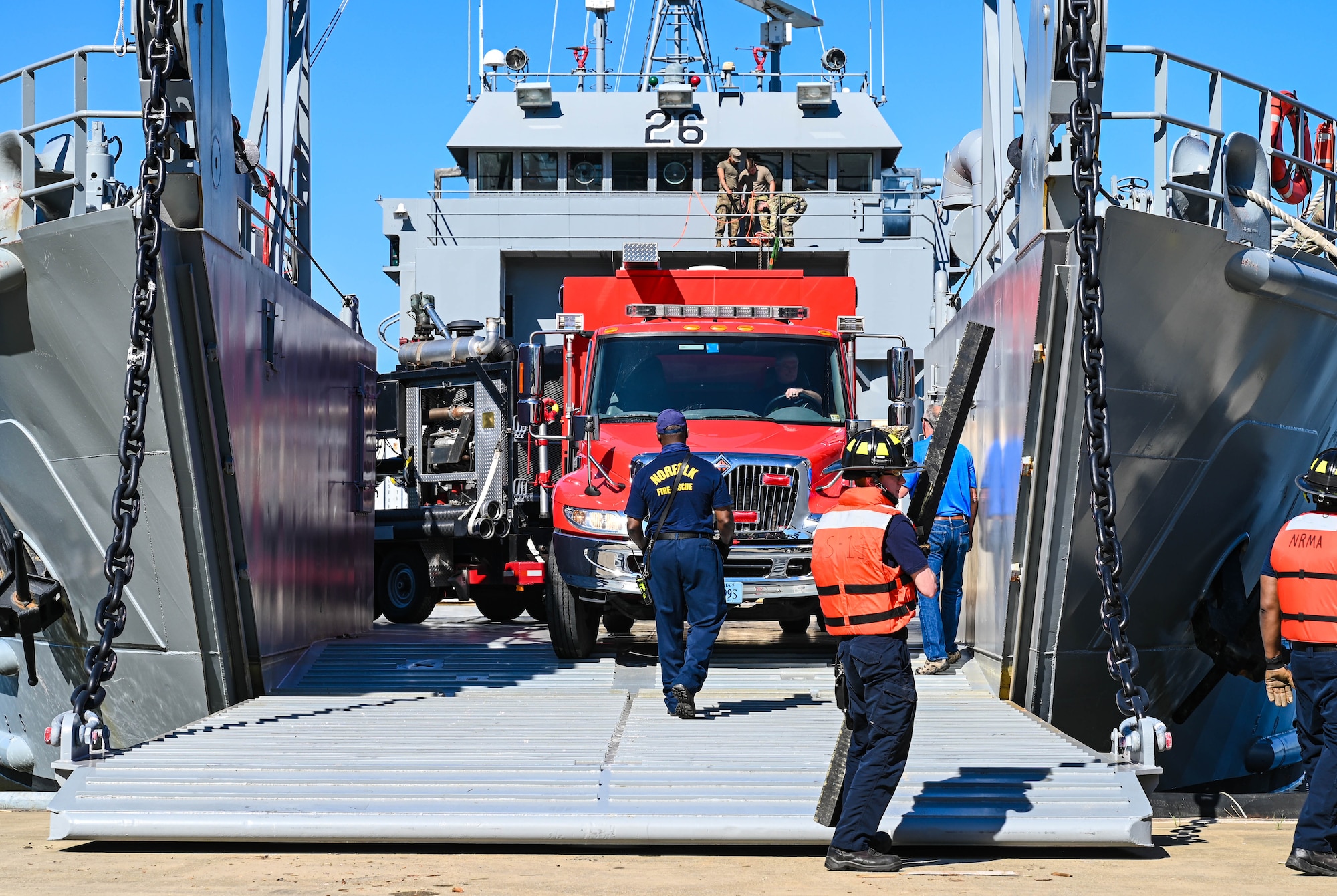 Firefighters from multiple agencies load a fire truck and pump trailer during the Robert E. Rumens Marine Firefighting Symposium at Joint Base Langley-Eustis, Virginia, May 21, 2021. This training was a stepping stone for land firefighters to begin learning maritime firefighting and advance their skill sets. (U.S. Air Force photo by Senior Airman Sarah Dowe)