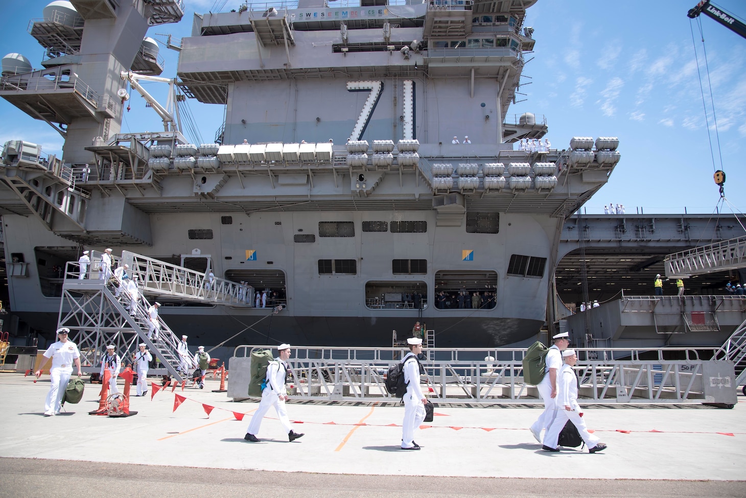 Sailor assigned to the Nimitz-class aircraft carrier USS Theodore Roosevelt (CVN 71) walk on the pier.