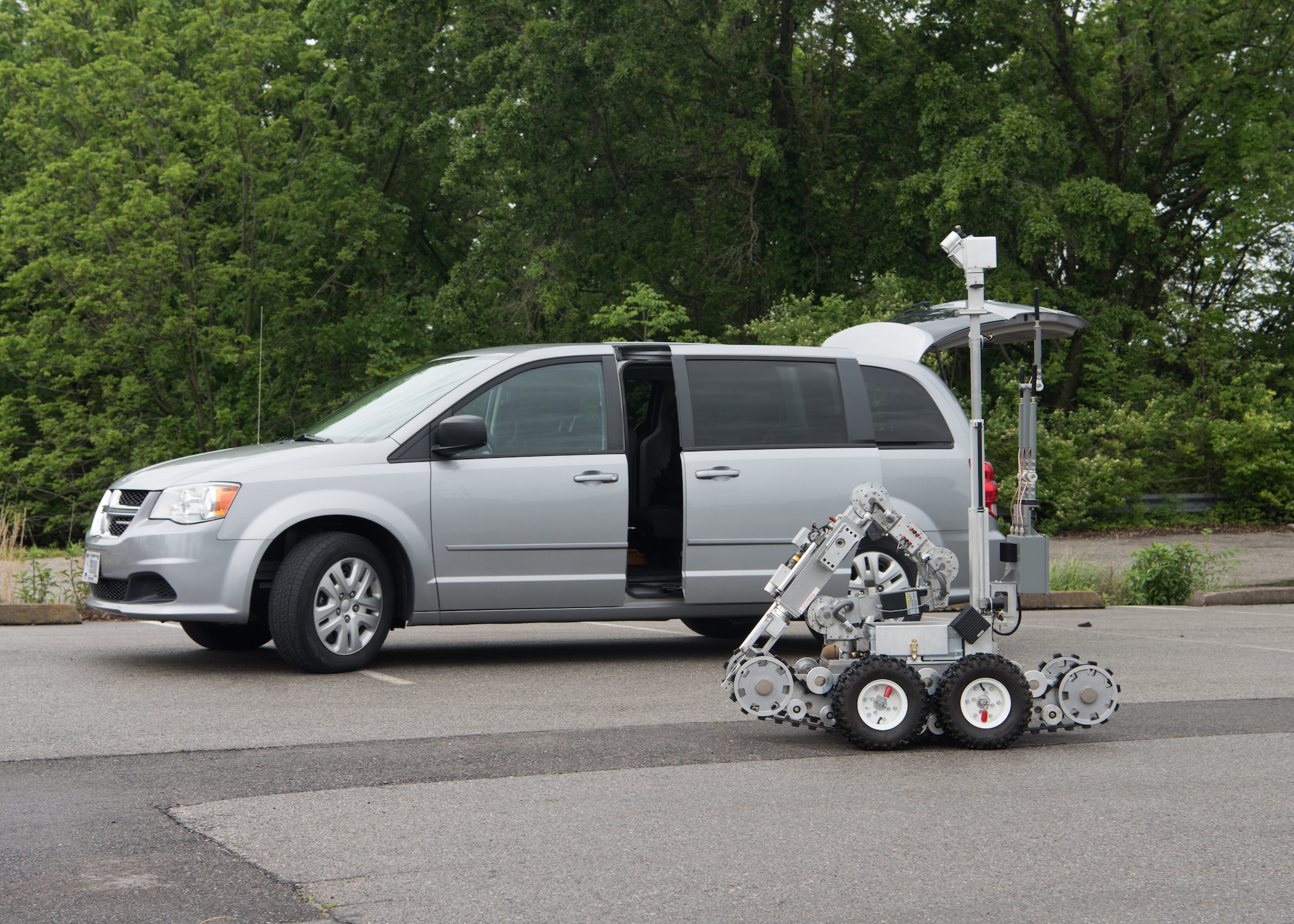 An explosive ordnance disposal robot drives past a minvan.
