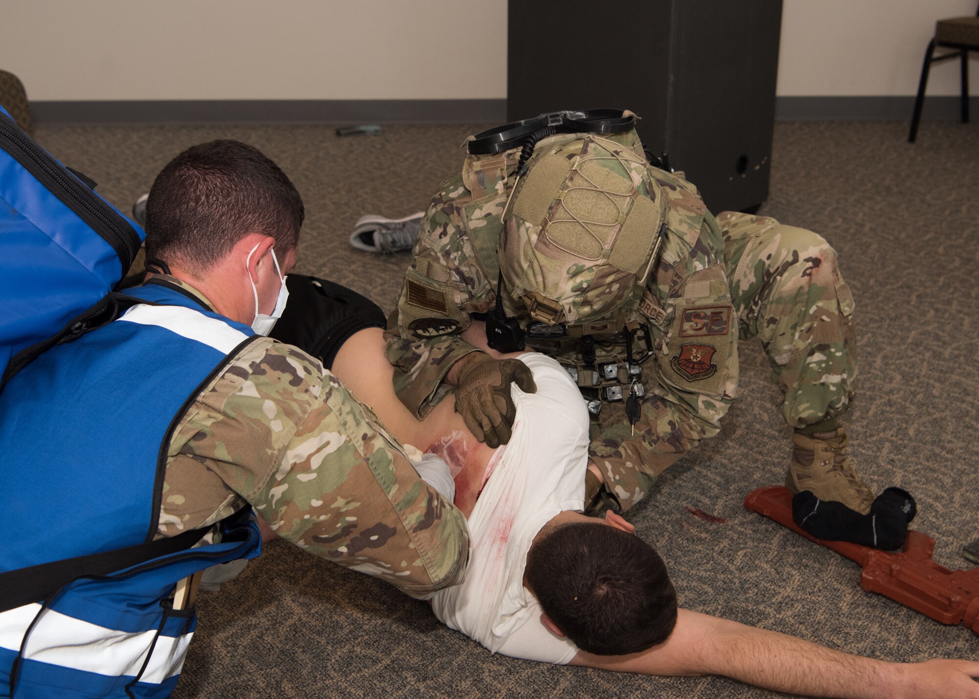 Two Airmen treat a the wounds of a simulated casualty.