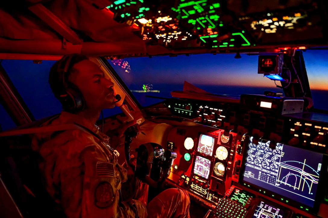 An airman sits inside the cockpit of an airborne aircraft.