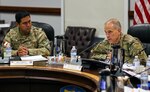 Two men, one U.S. Army, one Peruvian army, sitting at a table talking.