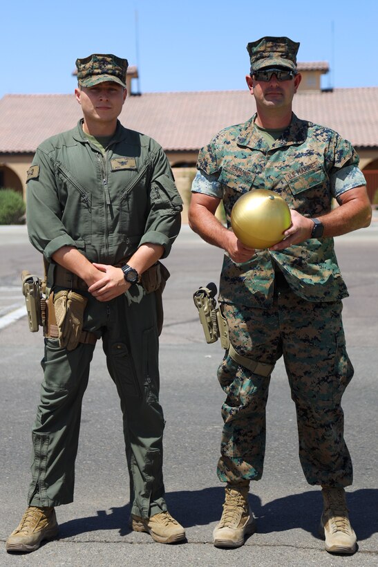 U.S. Marine Corps Cpl. Eric Sanchez, Left, and Staff Sgt. Aaron Seamons pose for a picture with the finial of the flagpole at Marine Corps Air Station Yuma, May 14, 2021. Placed inside the finial of the flagpole is a razor,  book of matches and a 9mm bullet. (U.S. Marine Corps photo by Lance Cpl. Matthew Romonoyske-Bean)