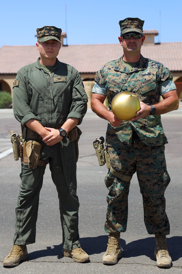U.S. Marine Corps Cpl. Eric Sanchez, Left, and Staff Sgt. Aaron Seamons pose for a picture with the finial of the flagpole at Marine Corps Air Station Yuma, May 14, 2021.