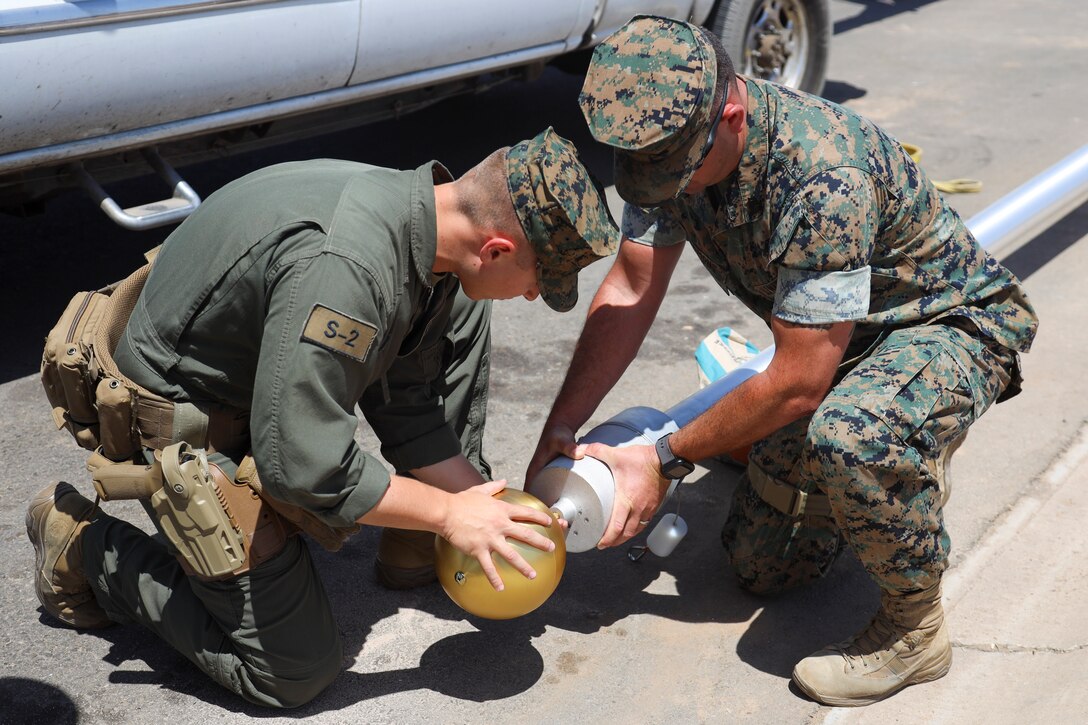 U.S. Marine Corps Cpl. Eric Sanchez and Staff Sgt. Aaron Seamons attach the finial of the flagpole at Marine Corps Air Station (MCAS) Yuma, May 14, 2021.