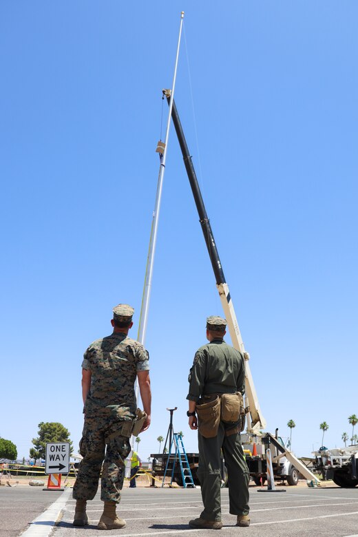 U.S. Marine Corps SSgt Aaron Seamons, Left, and Cpl Eric Sanchez observe the new flag pole being raised at Marine Corps Air Station Yuma, May 14, 2021. The newly installed flag pole stands at 80 feet tall. (U.S. Marine Corps photo by Lance Cpl. Matthew Romonoyske-Bean)