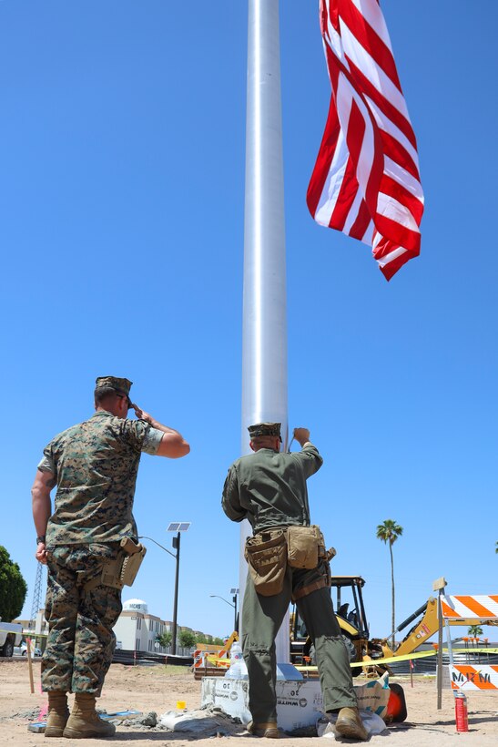 U.S. Marine Corps SSgt Aaron Seamons salutes as Cpl Eric Sanchez raises colors for the first time on the new flag pole at Marine Corps Air Station Yuma, May 14, 2021. Raising colors on military installations is a time-honored tradition. (U.S. Marine Corps photo by Lance Cpl. Matthew Romonoyske-Bean)