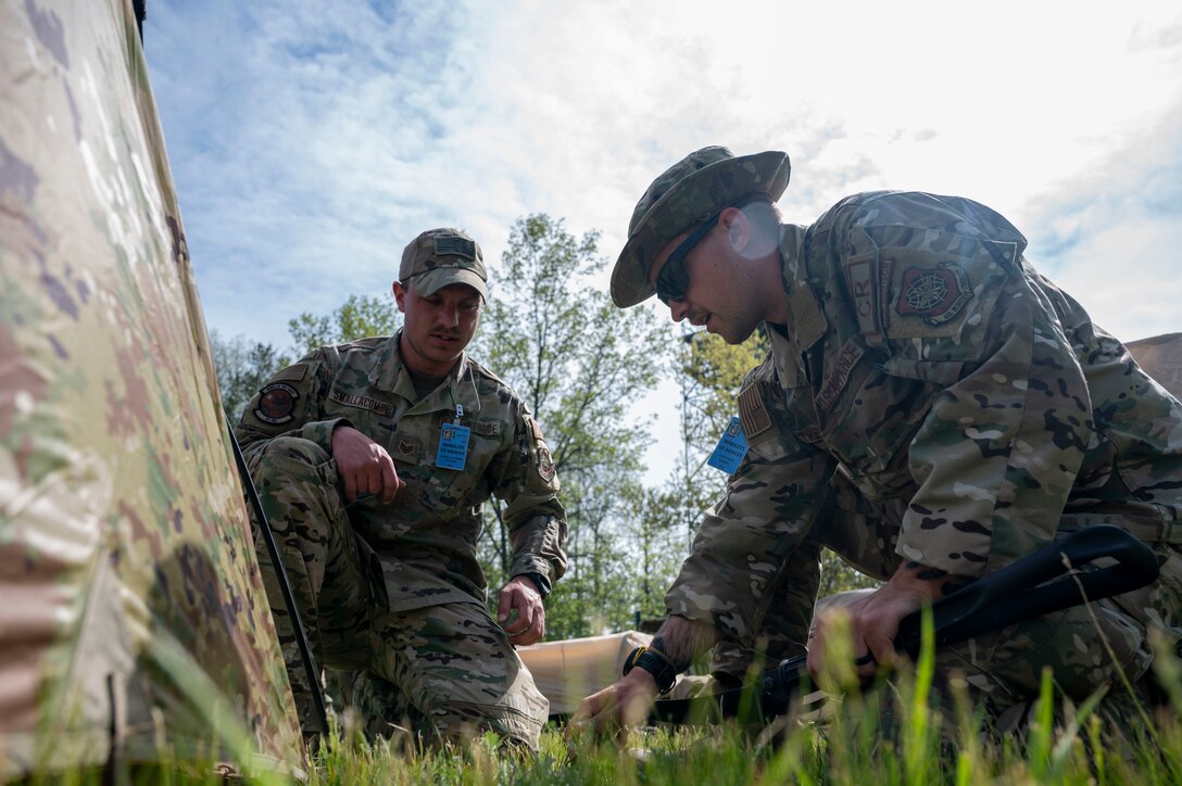 U.S. Air Force Staff Sgt. Steven Smallcombe, left, and Staff Sgt. Daniel Thevenet, right, 321st Contingency Response Squadron close precision engagement team members, setup a tent at Alpena Combat Readiness Training Center, Michigan, May 23, 2021, during Exercise Mobility Guardian 2021. The team is custom designed to roll out the back of a mobility aircraft with everything needed to operate for a few days while gaining command and control of an airfield to begin supporting the joint force with a minimal footprint. (U.S. Air Force photo by Senior Airman Aaron Irvin)