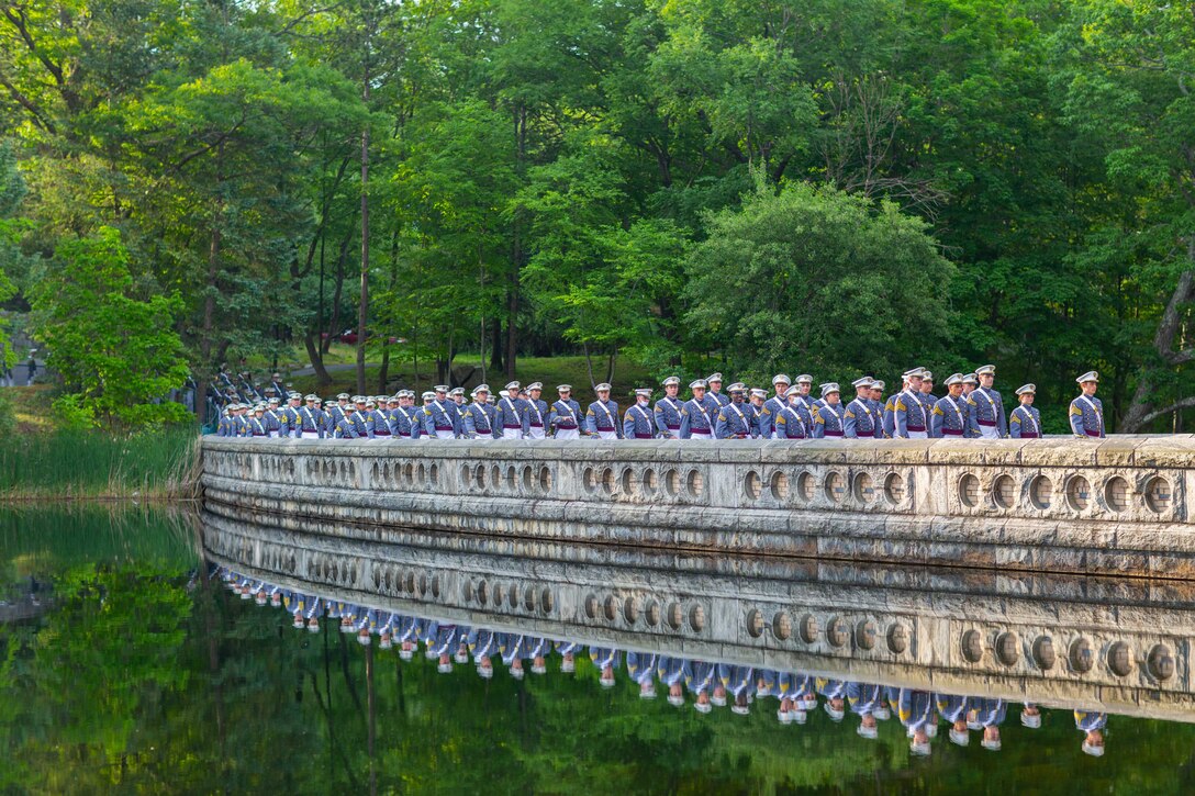 A group of Army cadets are reflected as they march across a bridge.