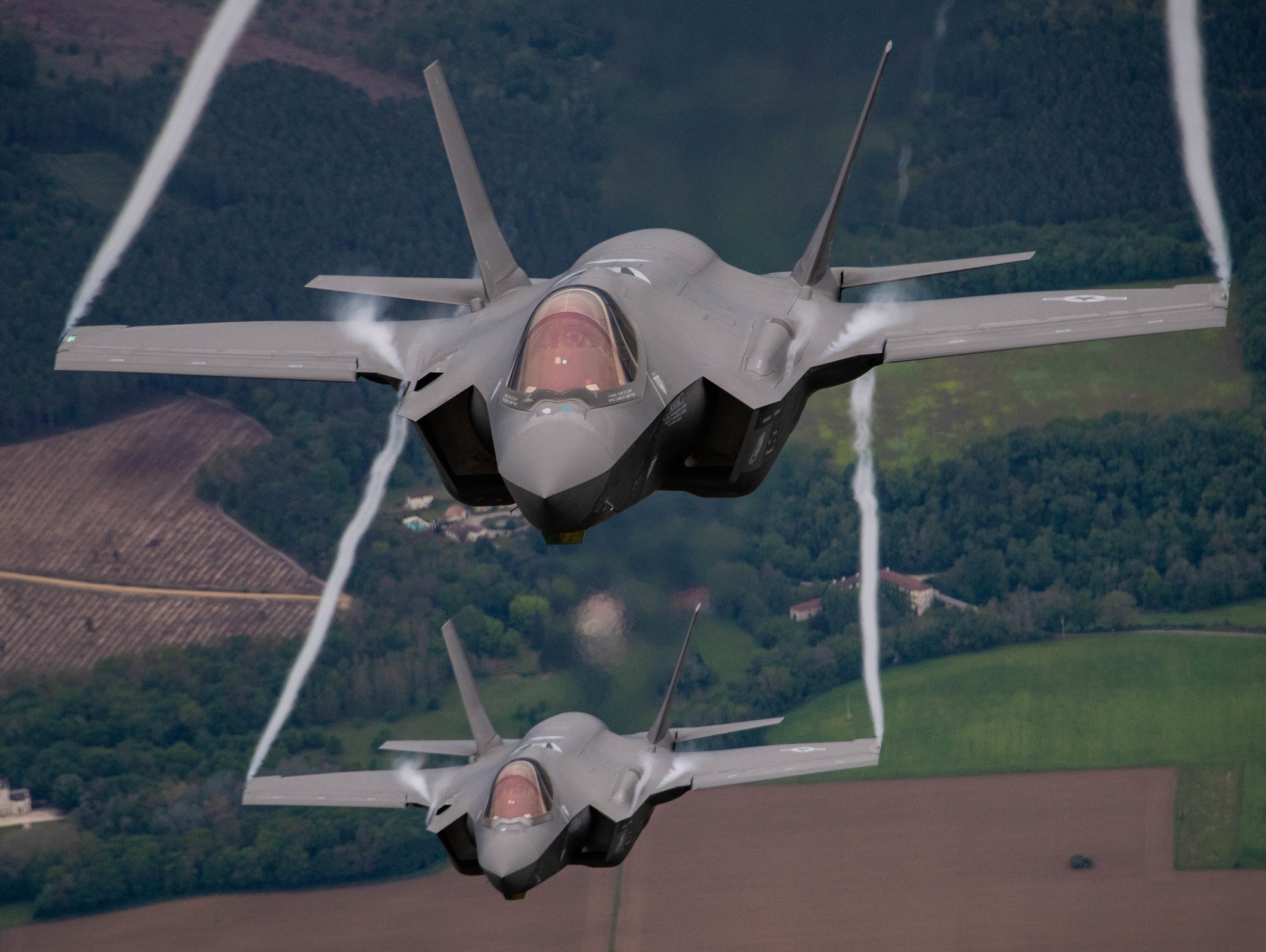 Two fighter aircraft flying towards the camera, one on top of the other.