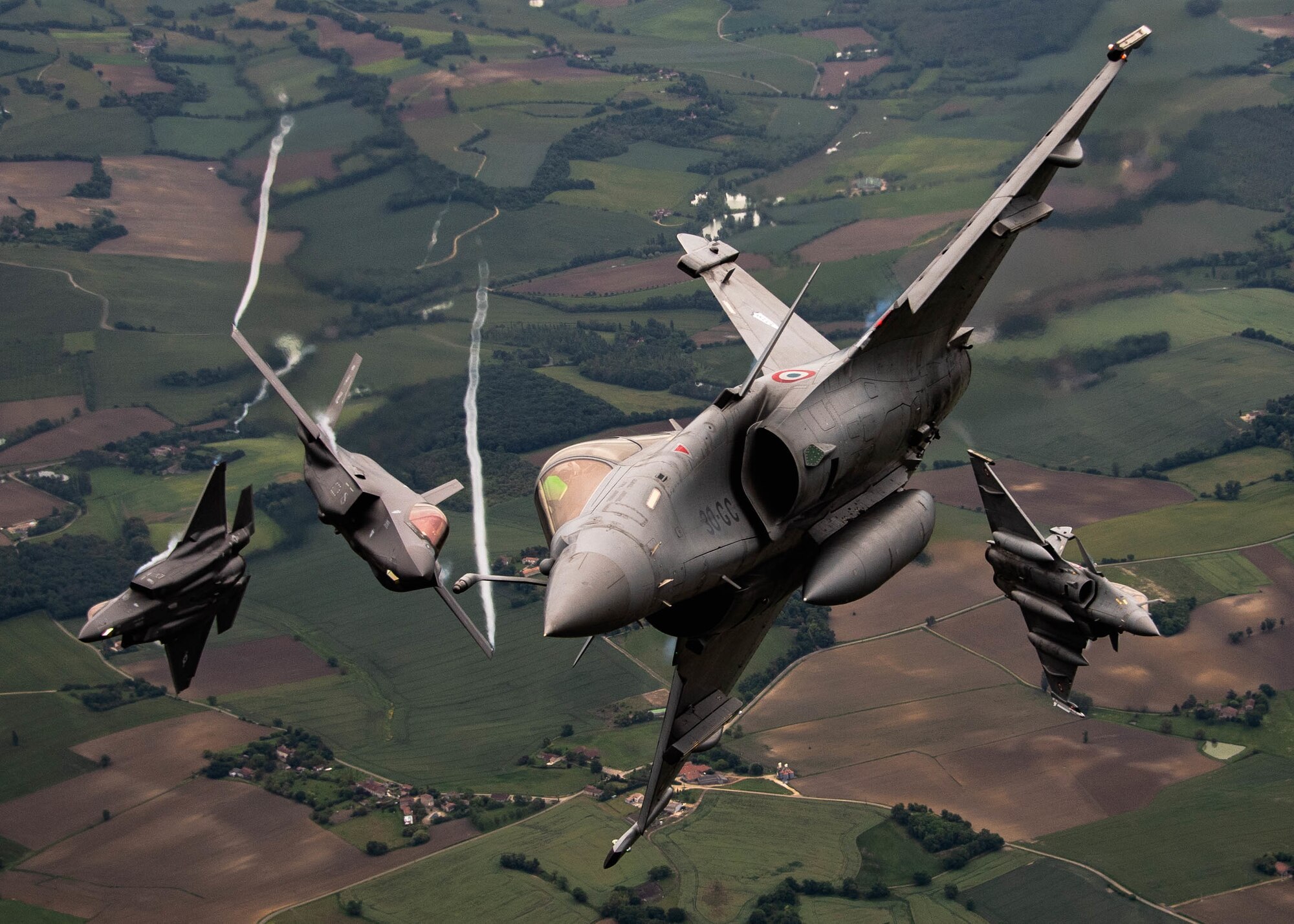 four fighter aircraft flying towards the camera, tilted as if all about to fly around the photographer.