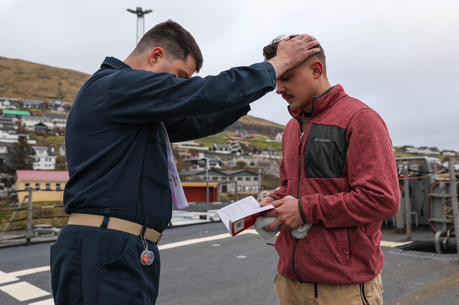 Hospital Corpsman 3rd Class Jonathan Scripp, right, is baptised by Lt. Joshua Johnson, the Chaplain aboard the Arleigh Burke-class guided-missile destroyer USS Ross (DDG 71), in a reaffirmation of baptism ceremony using the ship’s bell while in port in the Faroe Islands, May 15, 2021.