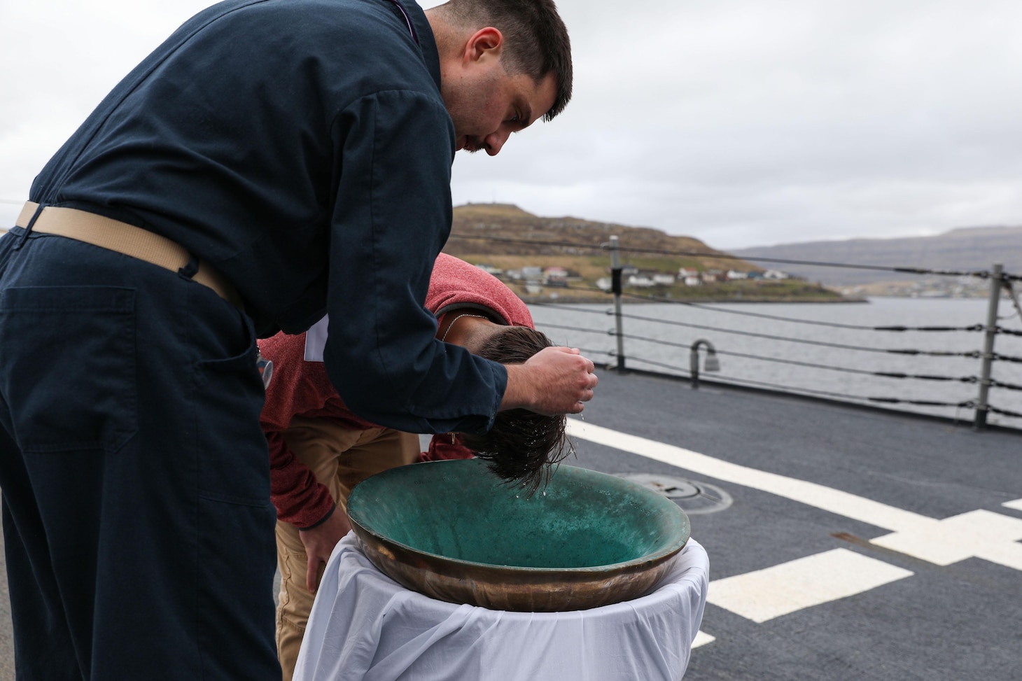 Hospital Corpsman 3rd Class Jonathan Scripp, right, is baptised by Lt. Joshua Johnson, the Chaplain aboard the Arleigh Burke-class guided-missile destroyer USS Ross (DDG 71), in a reaffirmation of baptism ceremony using the ship’s bell while in port in the Faroe Islands, May 15, 2021.