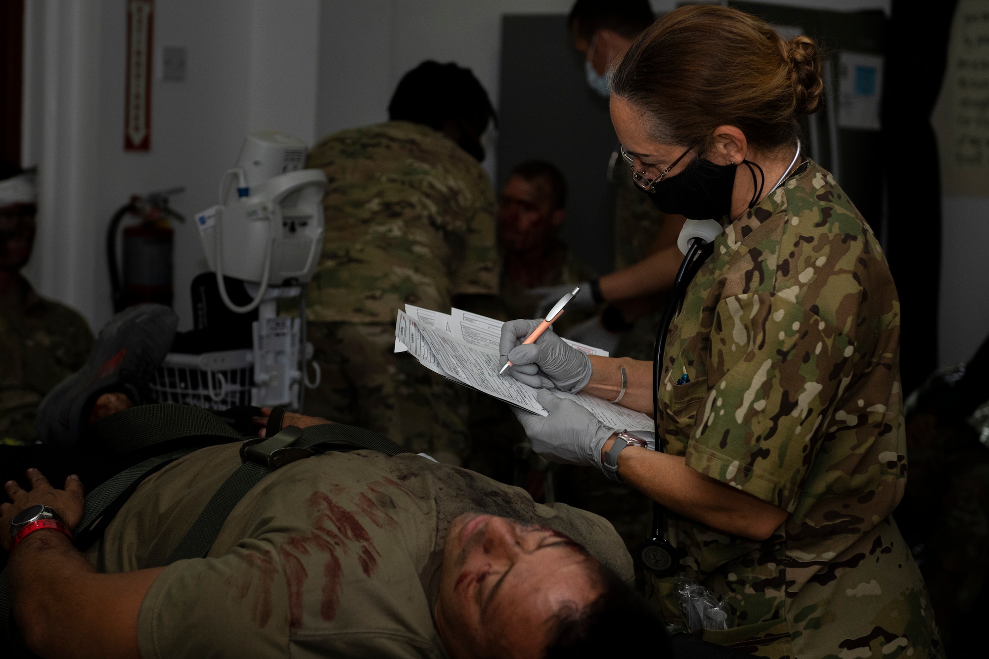 Medical personnel holds a clipboard over a simulated patient.