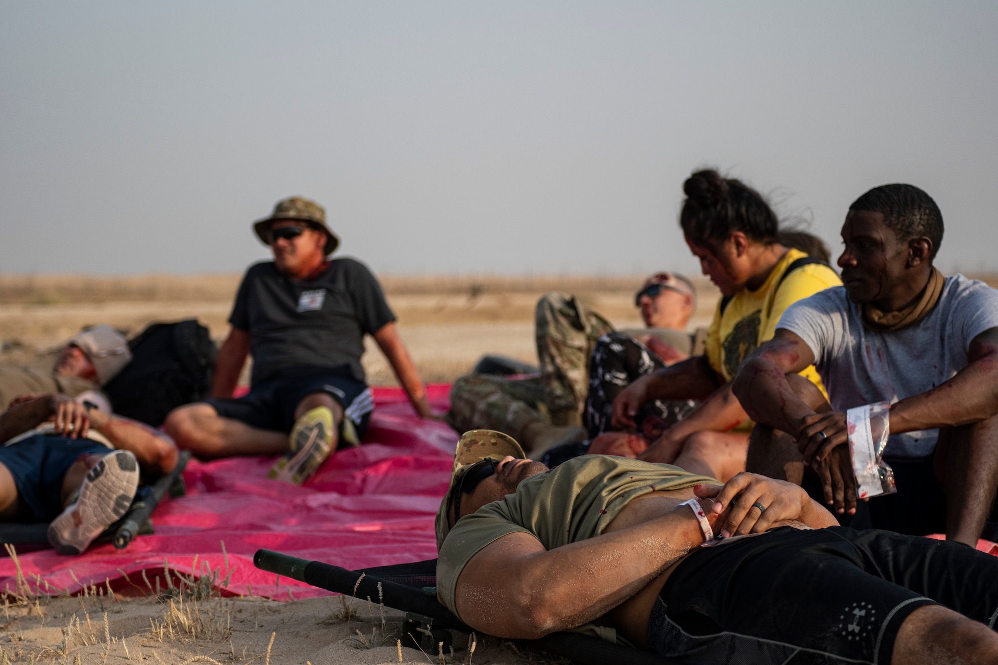 Volunteers acting as casualties with simulated injuries gather in the desert.