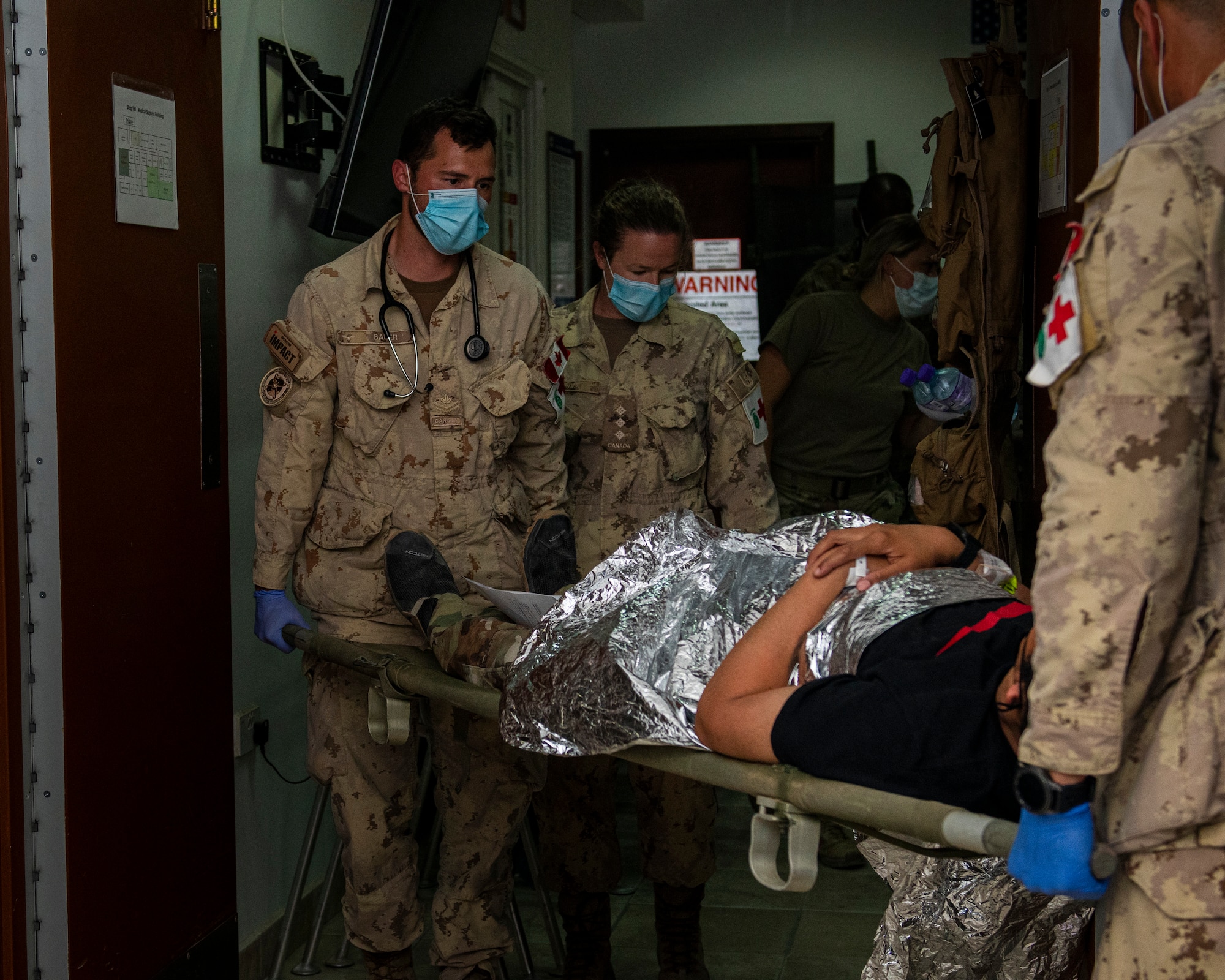 Medical personnel carry a stretcher into a room.