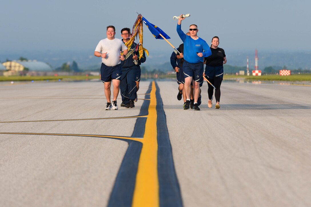 Airmen assigned to the 724th Aircraft Maintenance Squadron run in formation during a ‘Port Dawg’ memorial run at Aviano Air Base, Italy, May 27, 2021. The ‘Port Dawg’ memorial is an annual event which honors 12 fallen teammates with a 2.5 mile run. The path of the run took participants across the flight line, ending at the 724th AMS terminal. (U.S. Air Force photo by Airman 1st Class Brooke Moeder