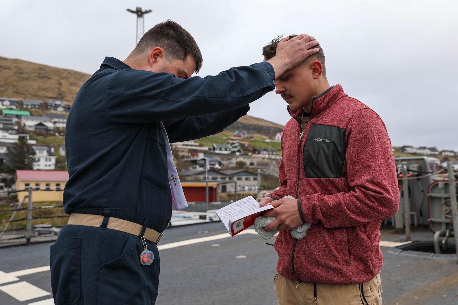 Hospital Corpsman 3rd Class Jonathan Scripp, right, is baptised by Lt. Joshua Johnson, the Chaplain aboard the Arleigh Burke-class guided-missile destroyer USS Ross (DDG 71), in a reaffirmation of baptism ceremony using the ship’s bell while in port in the Faroe Islands, May 15, 2021.