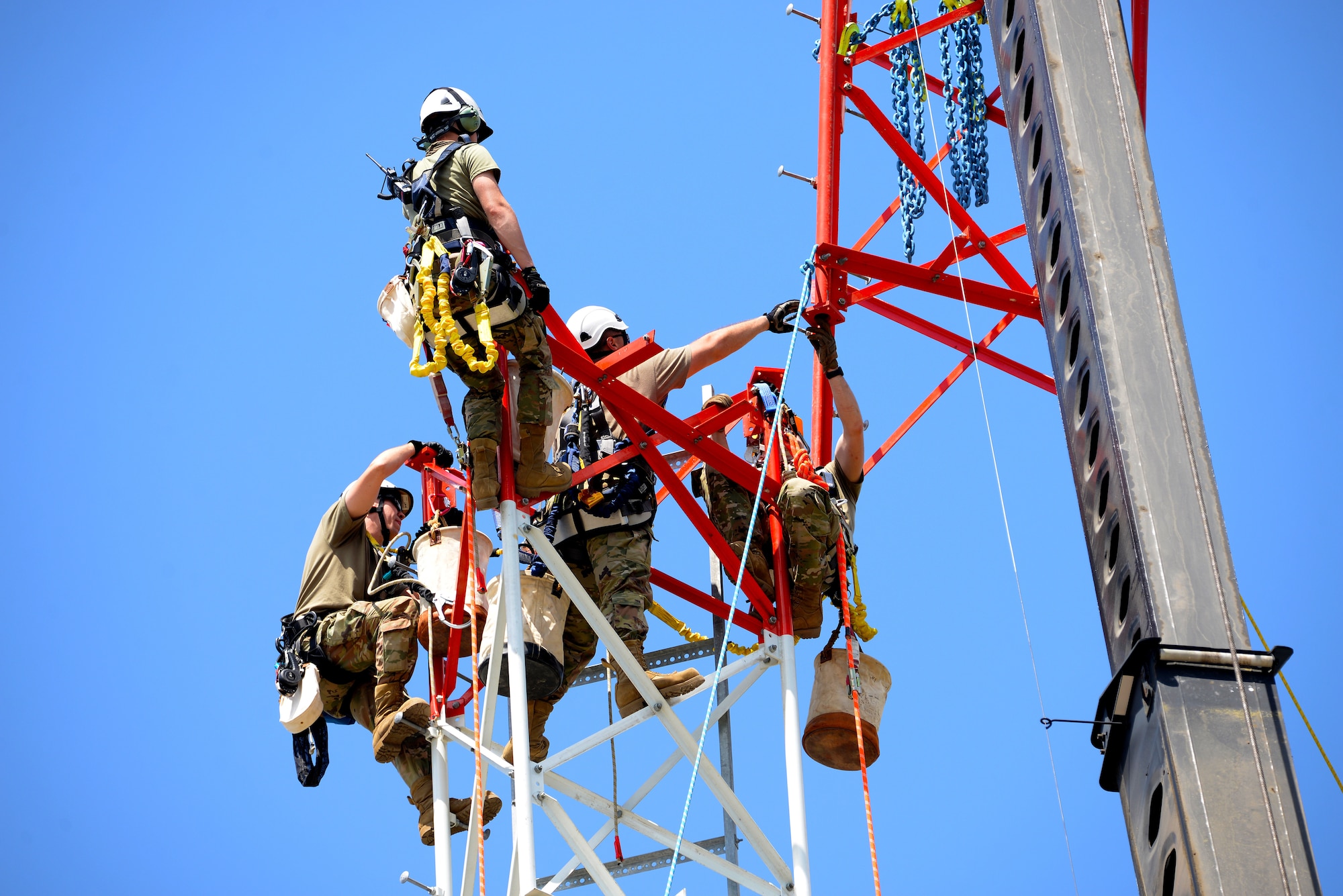 An image of Airmen connecting the final section of a radio communications tower.