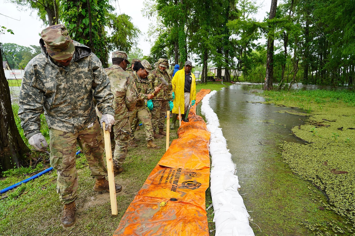 A group of service members set up a water-filled dam.