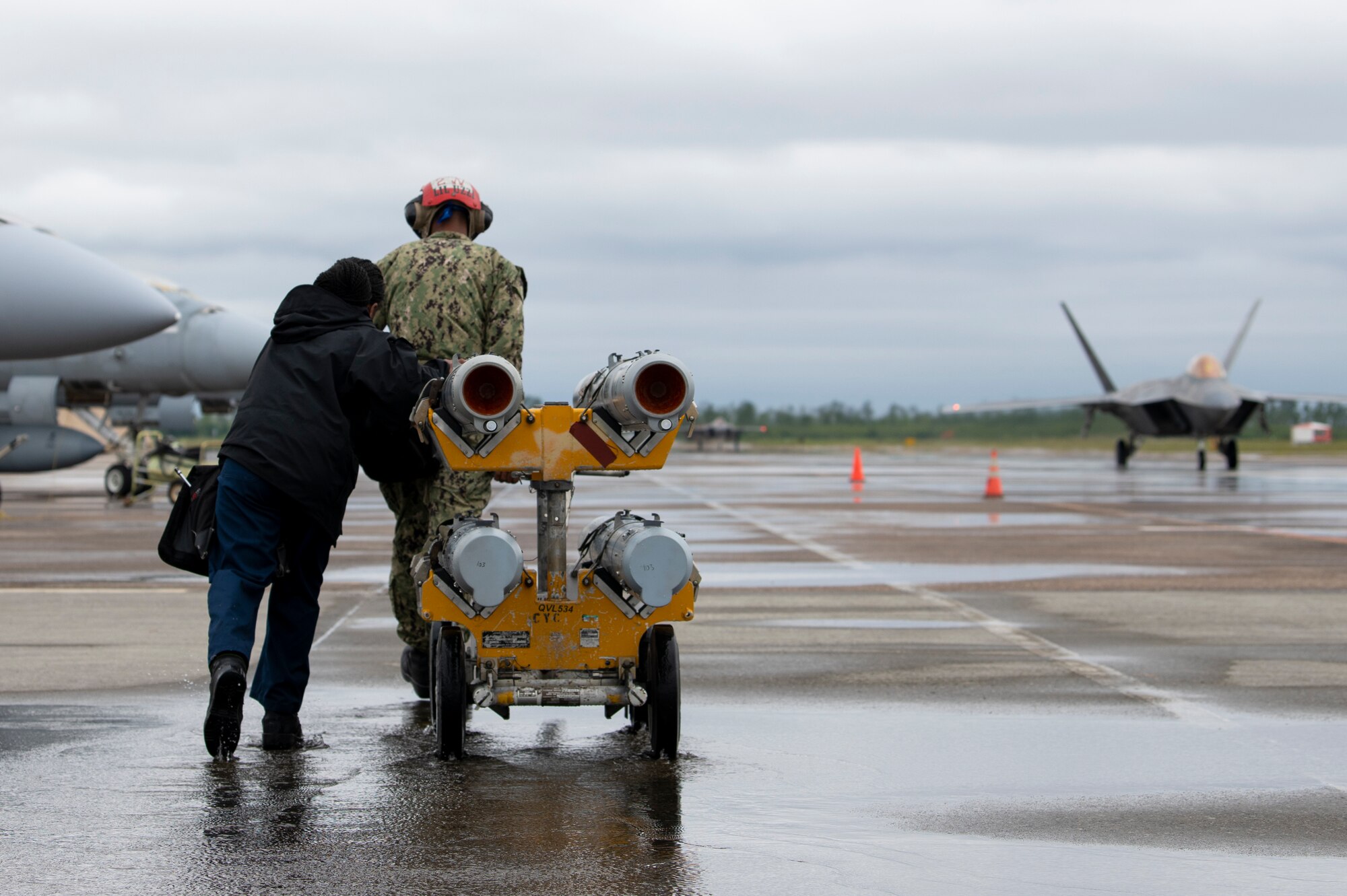 U.S. Navy Aviation ordnancemen pull a missile cart