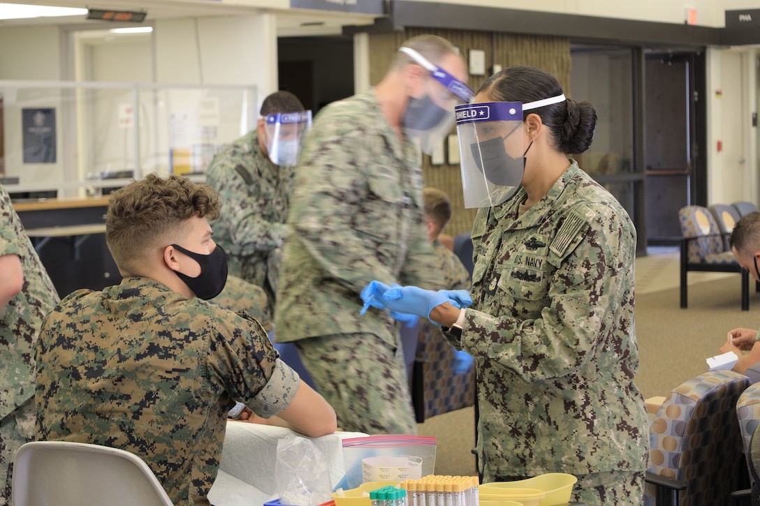 A sailor takes a blood sample from a Marine.