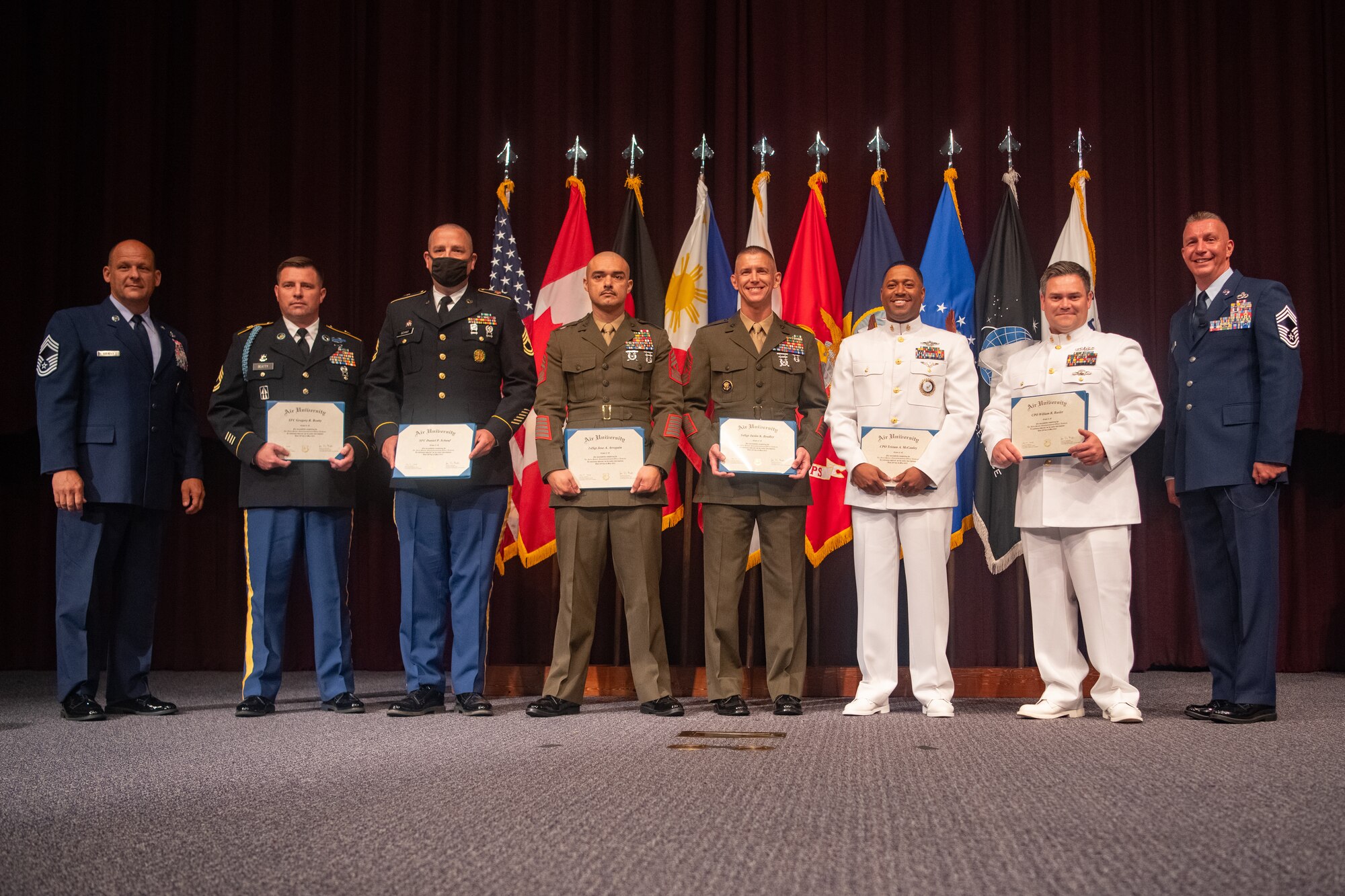 Chief Master Sgt. Gary Szekely, Senior Noncommissioned Officer Academy commandant, and Chief Master Sgt. Frank Graziano, the guest speaker for the Class 21-E graduation, pose for a photo with graduates of Class 21-E at a graduation ceremony at the SNCOA on Maxwell-Gunter Annex, Alabama, May 26, 2020. Among the precautionary measures taken in response to COVID-19, the SNCOA saw a major class size reduction from 280 students to about 170.