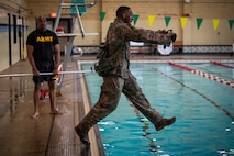 A male soldier crawls through an obstacle course.