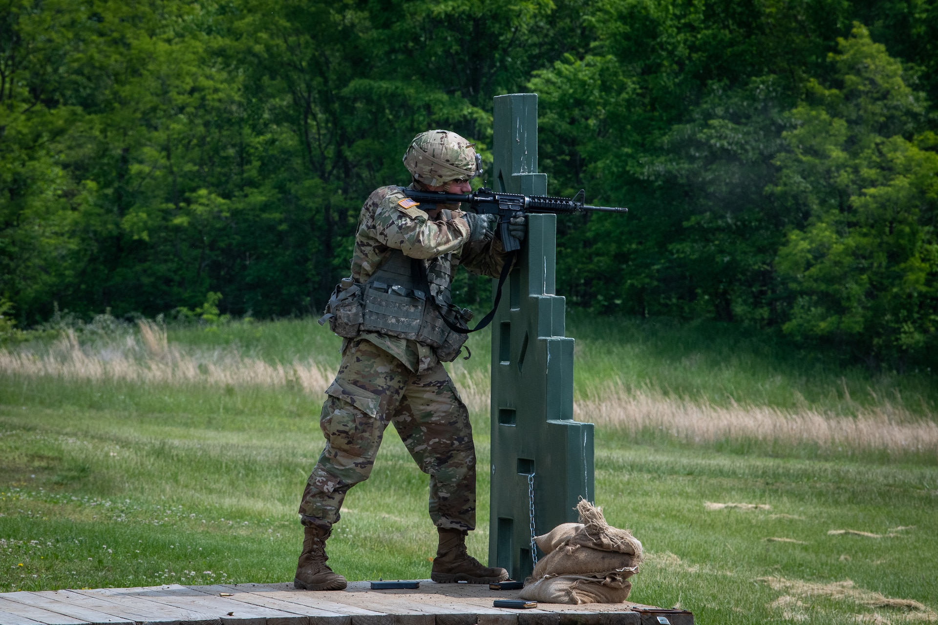 A male soldier crawls through an obstacle course.