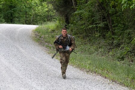 A male soldier crawls through an obstacle course.