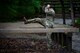 A male soldier crawls through an obstacle course.