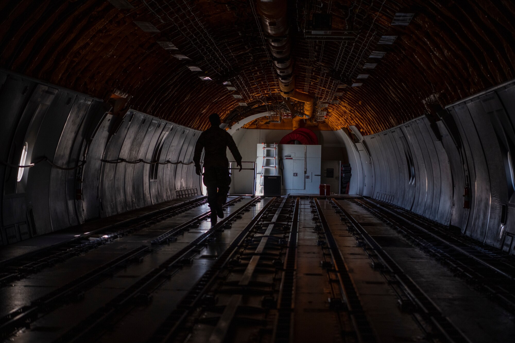 The silhouette of a man in the back of a large military aircraft.