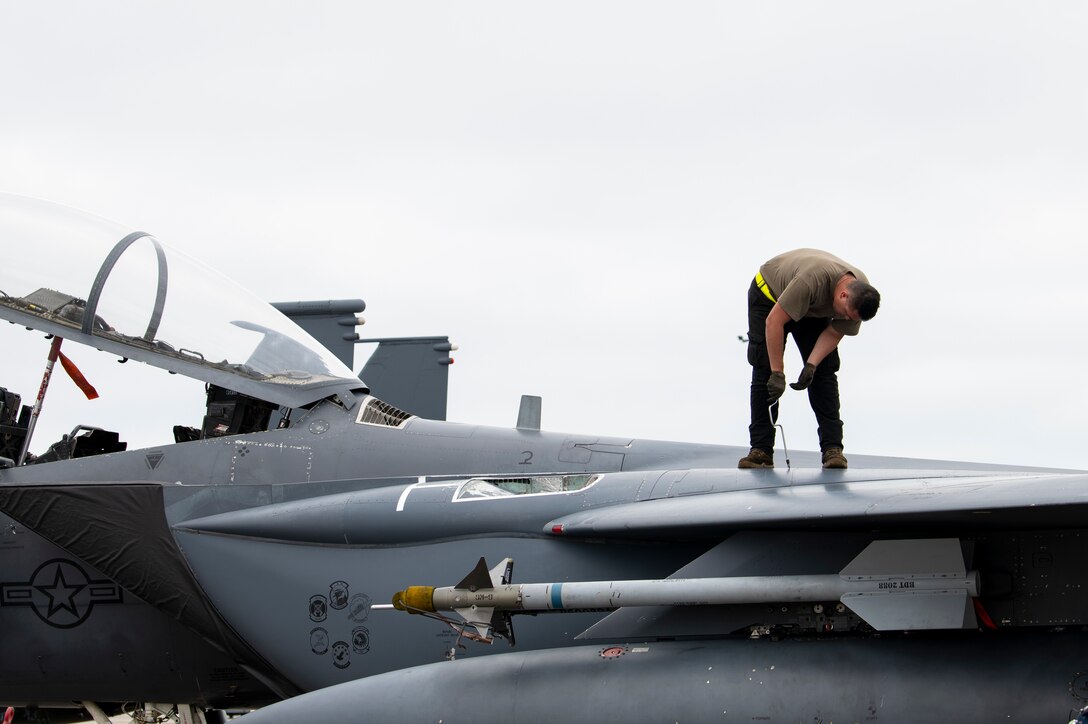 U.S. Air Force Airman stands on top of aircraft
