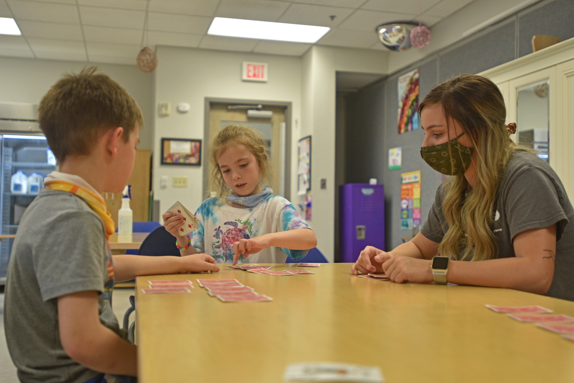 A child youth program assistant plays cards with two children at the School Age Program building on Goodfellow Air Force Base, Texas, April 27, 2021. The CYP assistants work directly with the kids, engaging and playing with them while assisting them in any way when they are at the School Age Program. (U.S. Air Force photo by Senior Airman Ashley Thrash)