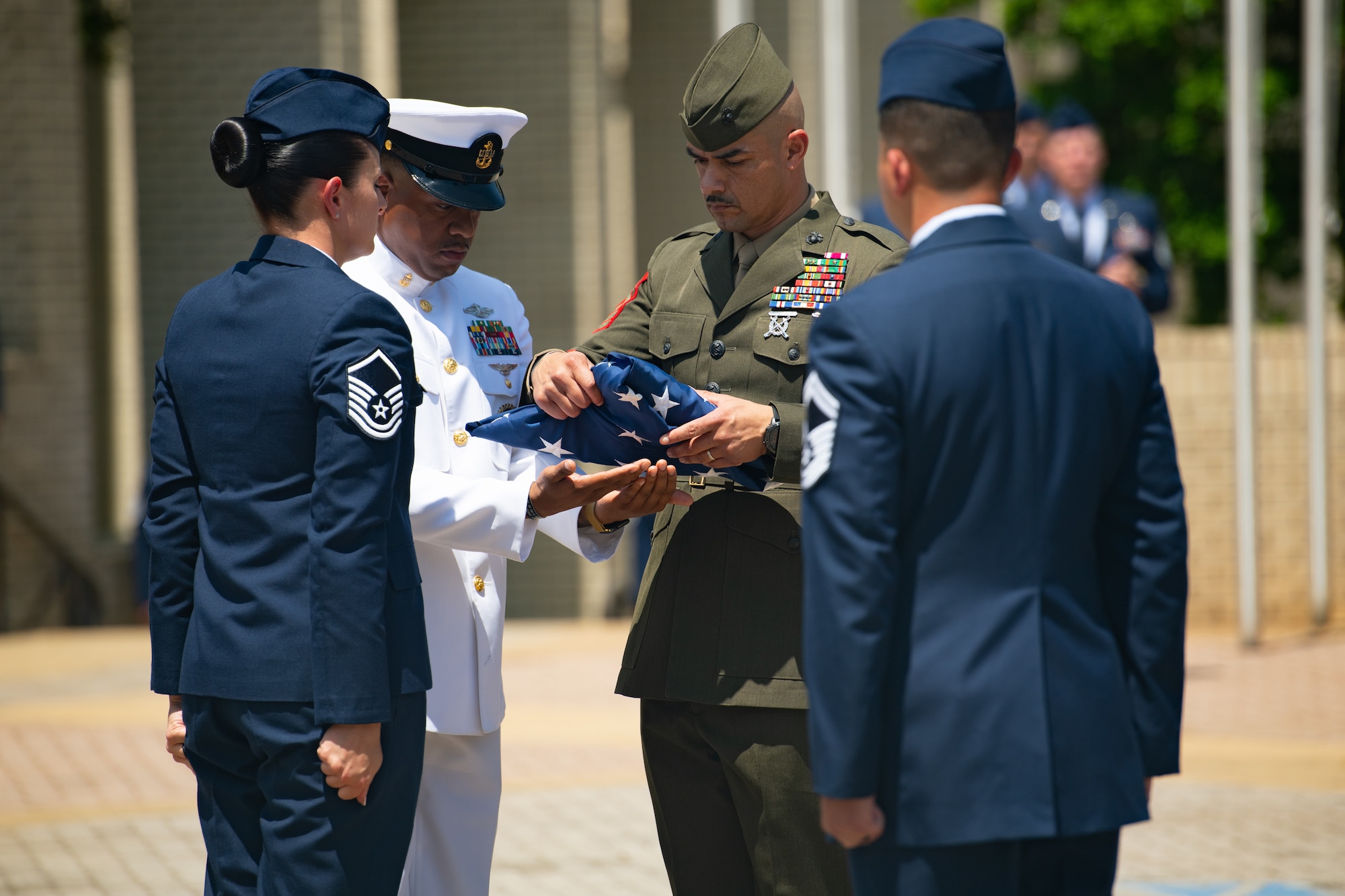 Graduates with Class 21-E fold the flag during a retreat ceremony after their graduation from the Senior Noncommissioned Officer Academy on Maxwell-Gunter Annex, Alabama, May 26, 2020. Retreat ceremonies serve a twofold purpose: they signal the beginning and ending of the official duty day and serve as ceremonies for paying respect to the flag and those who serve it.