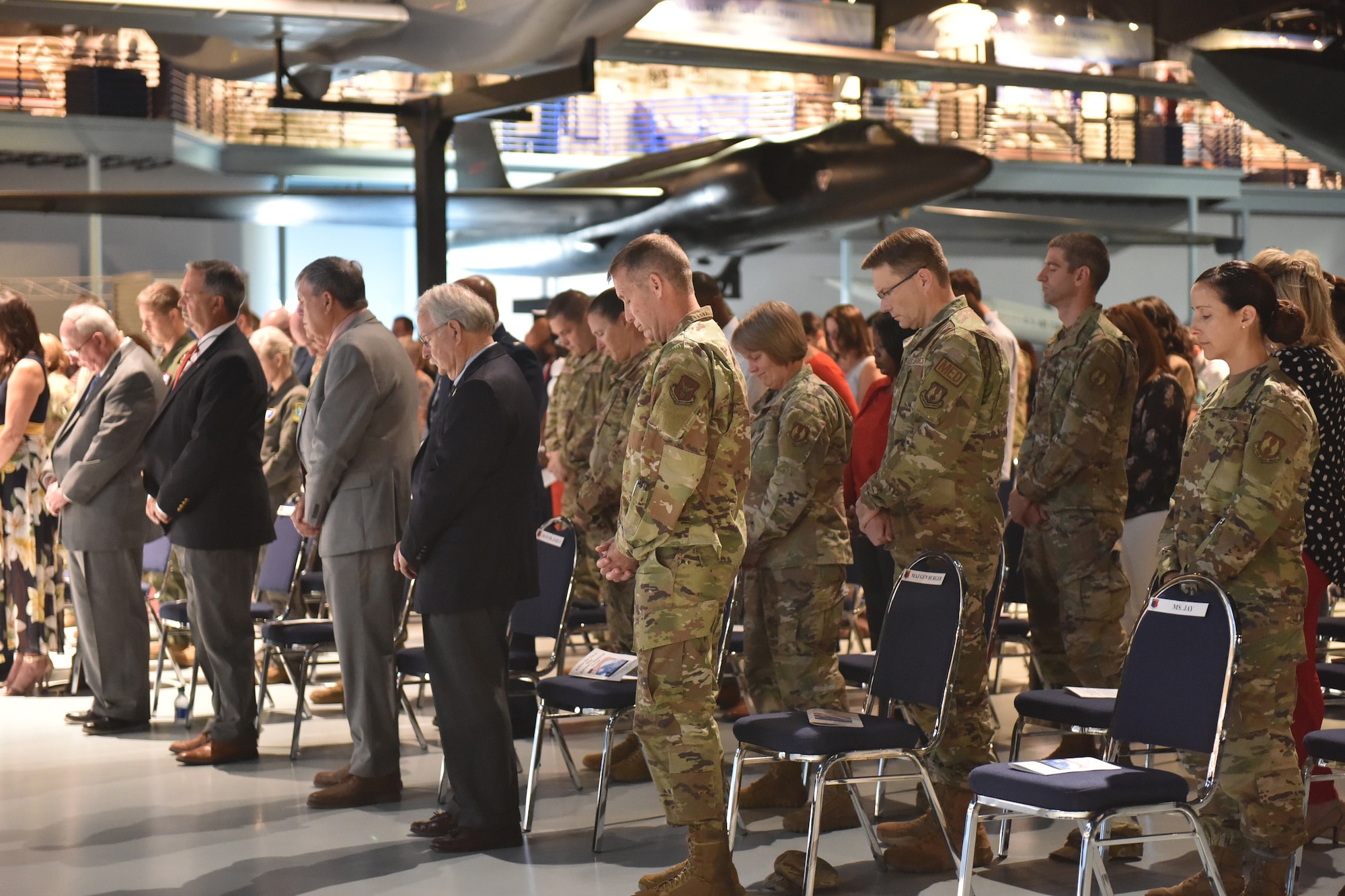 Photo shows crowd standing with heads bowed.