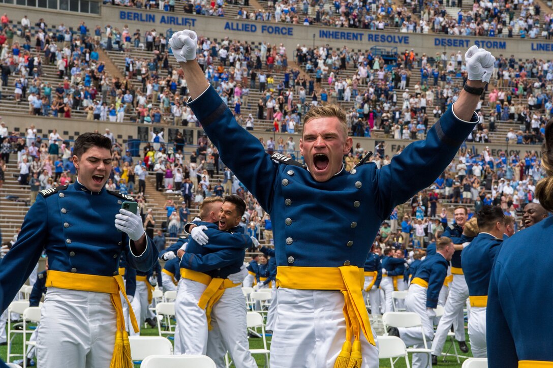 An airman shouts and pumps the air in celebration while another looks on.