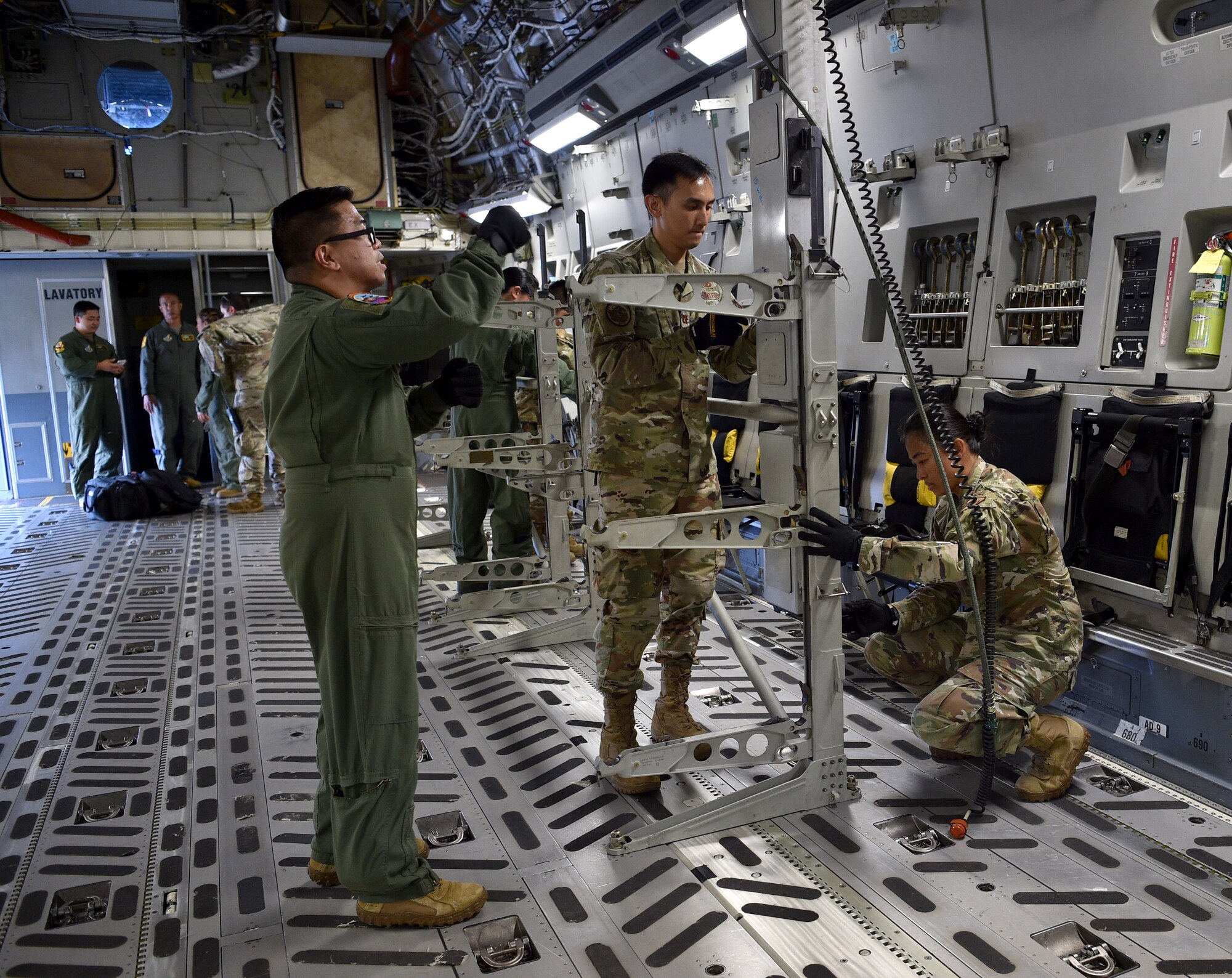 Major Joel Villavert, 613th Air Operations Center, Capt. John Penaranda, 624th Civil Engineer Squadron, and Capt. Louise Sarabosing, 624th Aeromedical Staging Squadron, prepare a C-17 for an aeromedical evacuation demonstration at Joint Base Pearl Harbor-Hickam, Hawaii, May 25, 2021. In honor of Asian American Pacific Islander Heritage Month, active duty, Air Force Reserve, and Air National Guard Airmen of Asian American and Pacific Islander descent came together to demonstrate Air Force capabilities for University of Hawaii ROTC cadets. (U.S. Air Force photo by 1st Lt. Amber R. Kelly-Herard)