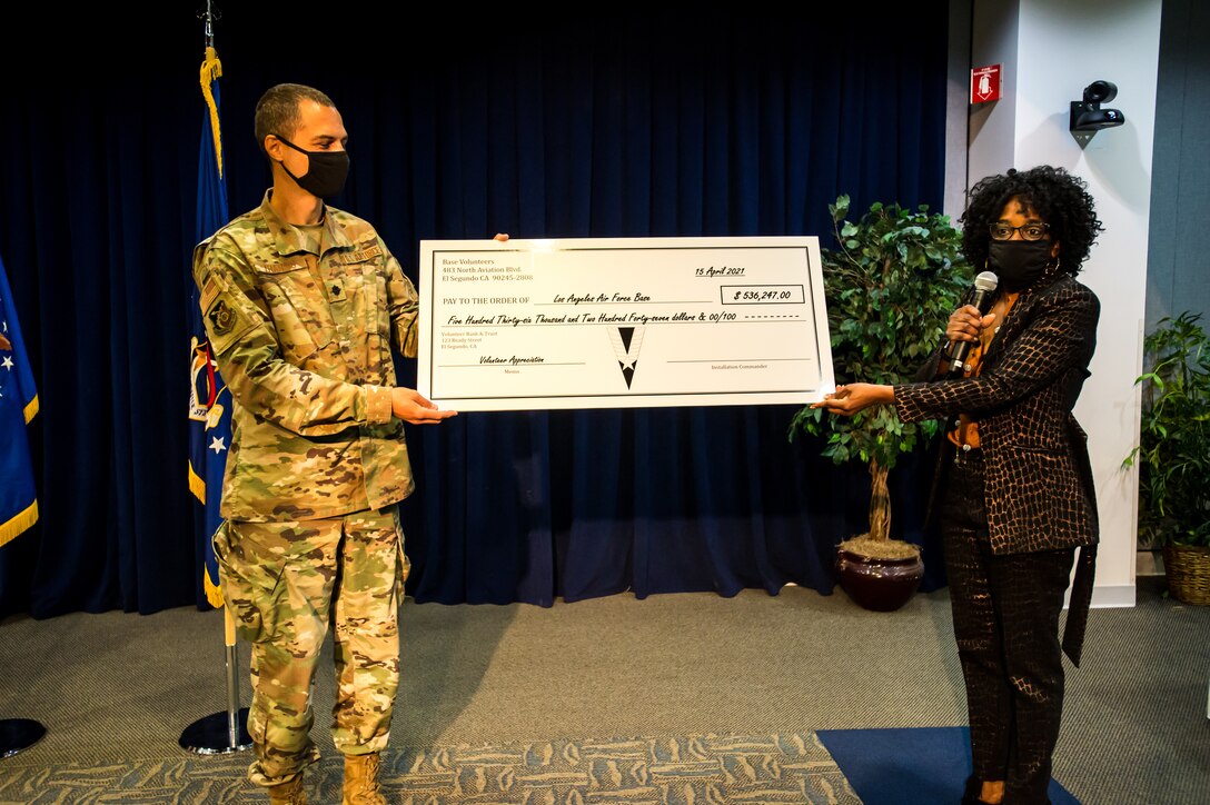 Lt. Col. John Francis, 61st Air Base Group IMA to the Deputy Commander and Ms. Cathy Howard, Flight Chief, Airman and Family Readiness, present a “cost savings” check for $536,247 to Los Angeles Air Force base which represent the 19,000 volunteer hours those individuals donated to the base during the Los Angeles Air Force Base Volunteer Appreciation Ceremony. (U.S. Space Force photo by Van Ha)
