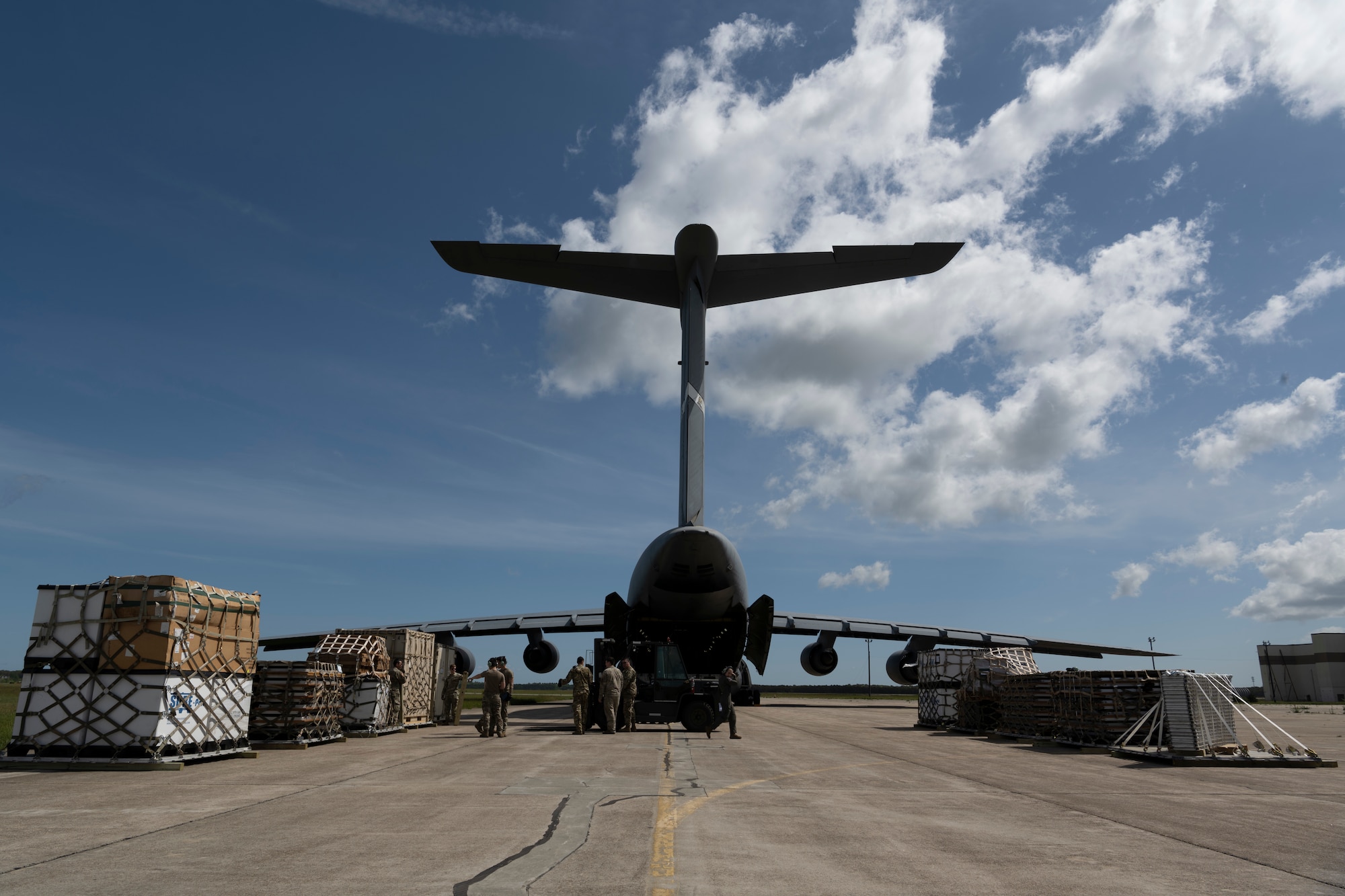 Airmen and cargo surrounding a plane